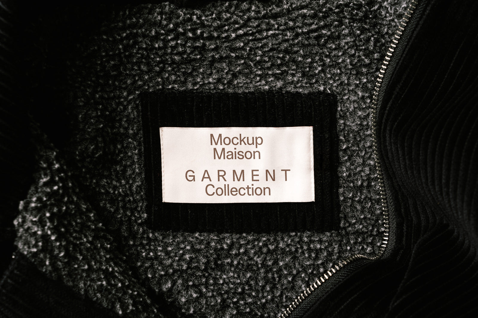 PSD mockup of a garment label inside a coat featuring "Mockup Maison GARMENT Collection," surrounded by soft, textured fabric and a zipper.