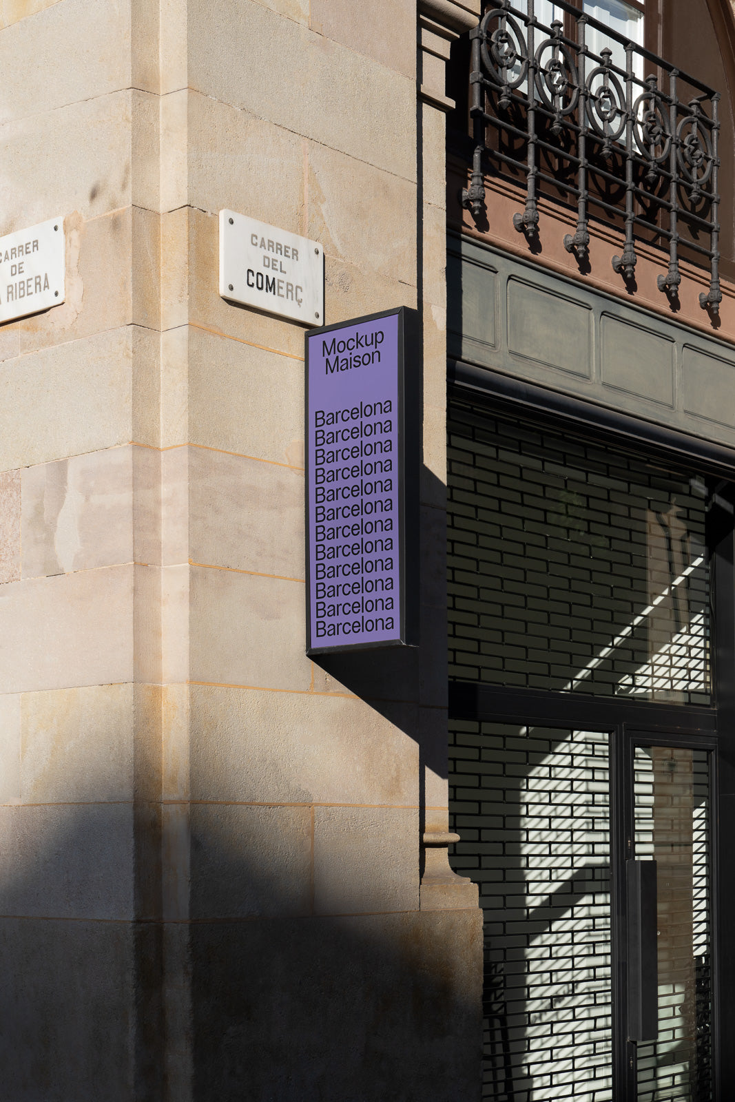 PSD mockup of a vertical sign on a building corner with "Mockup Maison" and "Barcelona" text, shadows cast on the stone facade.