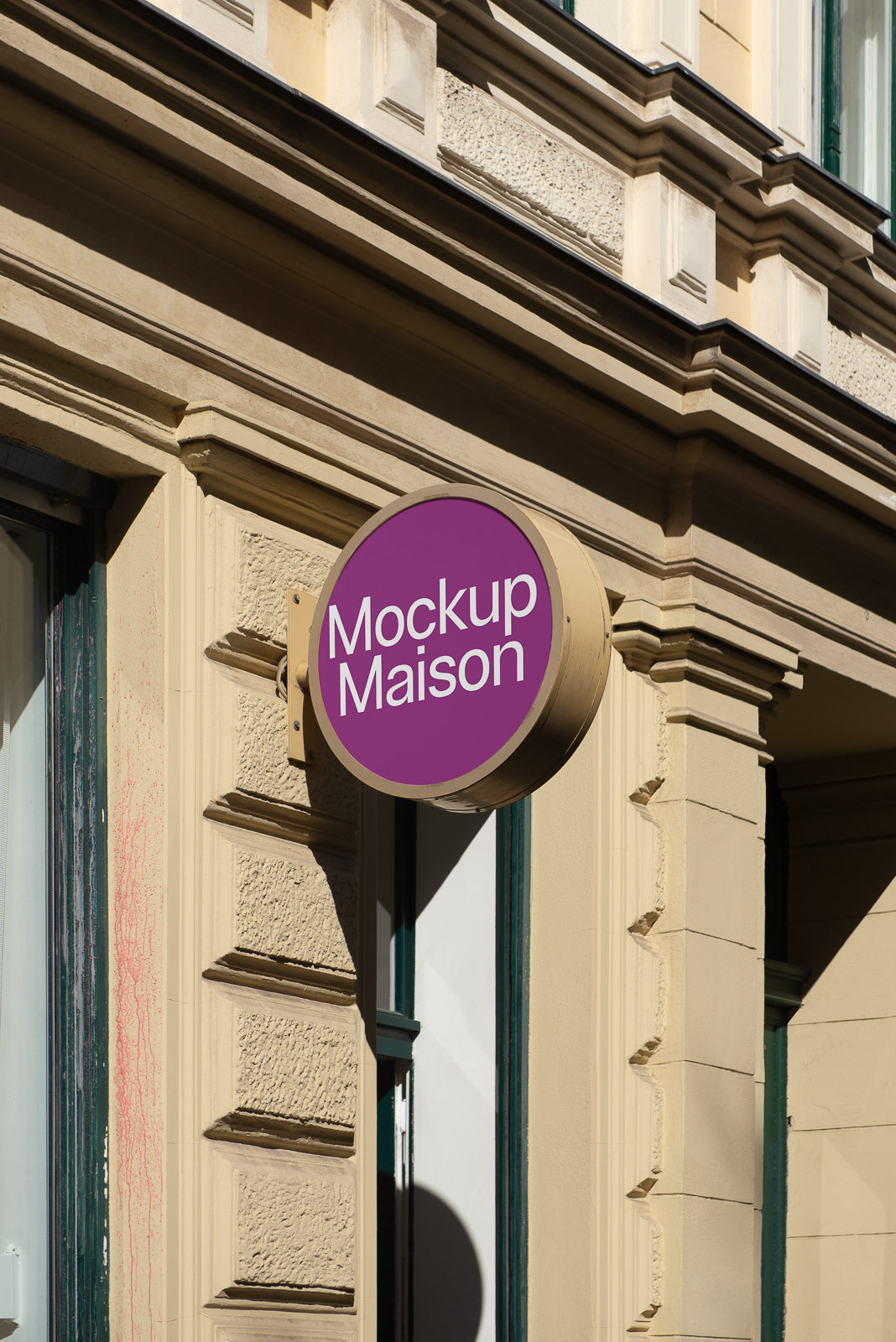 PSD mockup of a round, purple outdoor sign with the text "Mockup Maison" mounted on a beige building facade, casting a shadow.
