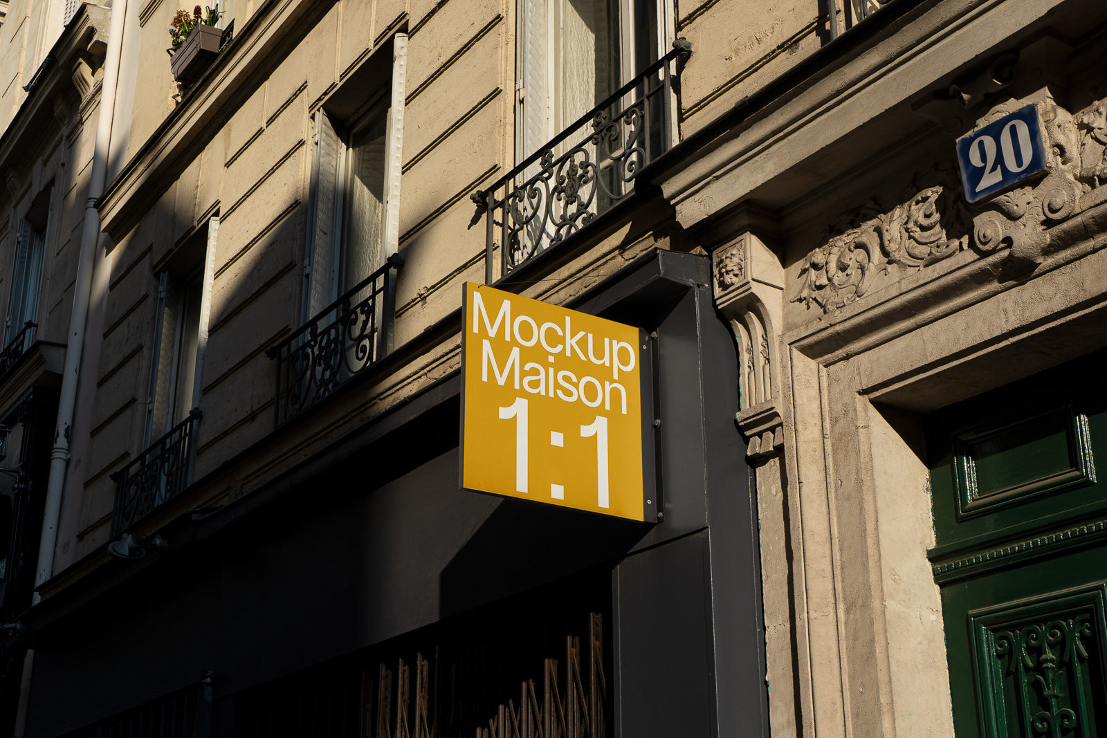 PSD mockup of a yellow store sign with "Mockup Maison 1:1" displayed on a building facade in partial shadow.
