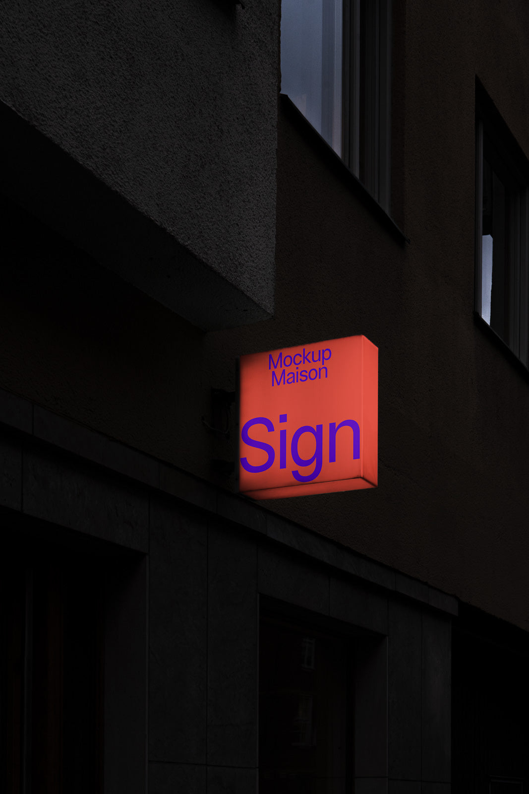 PSD mockup of an illuminated square sign on a dark building exterior, displaying text "Mockup Maison Sign" in large, bold letters.
