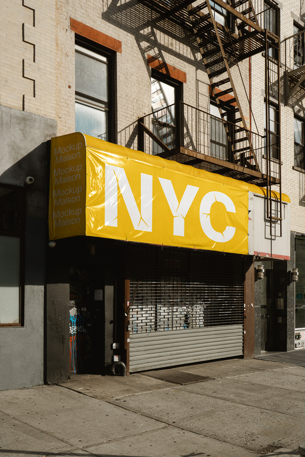 PSD mockup of a yellow storefront canopy with large "NYC" text and "Mockup Maison" repeated on the side, set against an urban building with a fire escape.