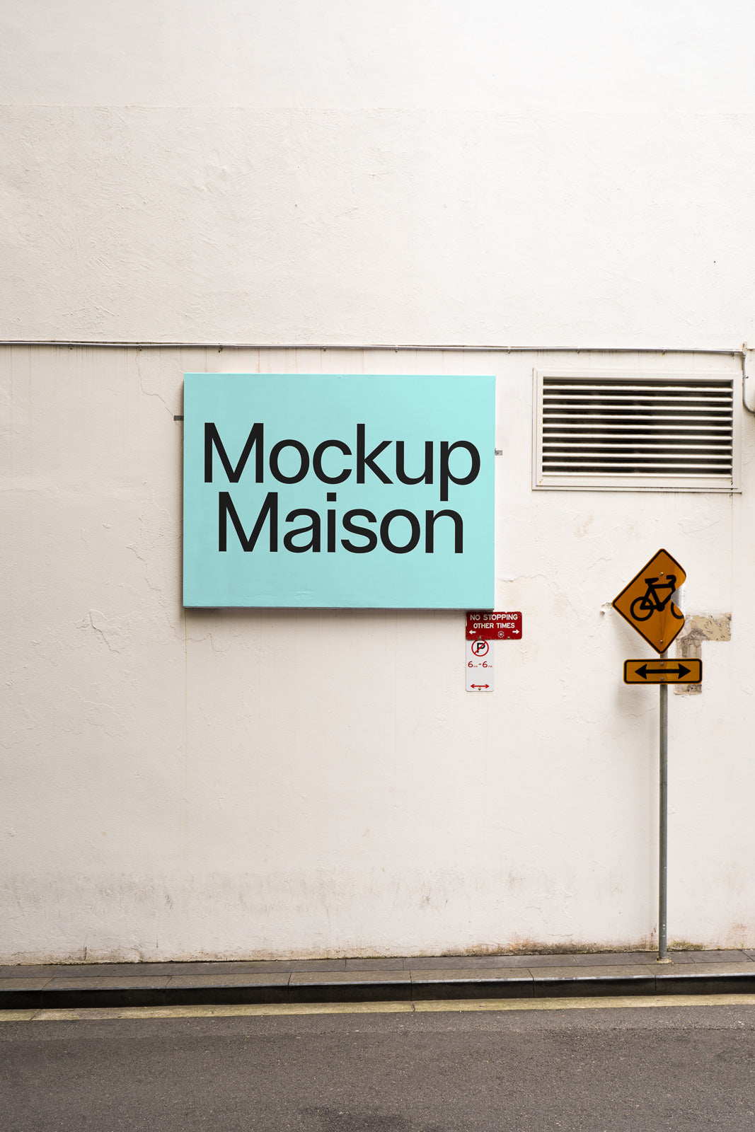 PSD mockup of a light blue sign on a textured white wall with "Mockup Maison" text, next to street signs with a bike symbol and arrows.