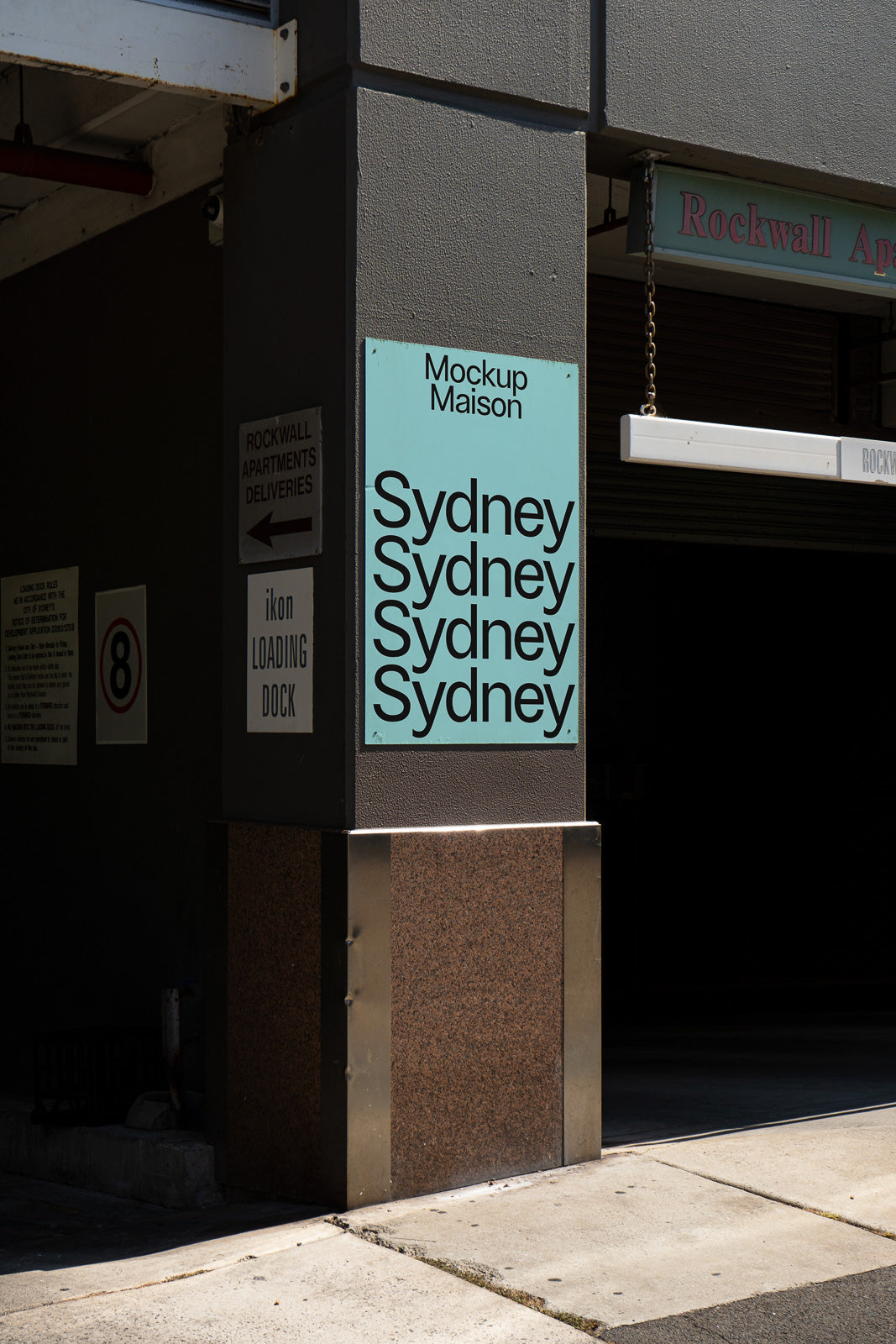 PSD mockup of a building facade with a turquoise sign reading "Sydney" multiple times, placed on a column beside a loading dock entrance.