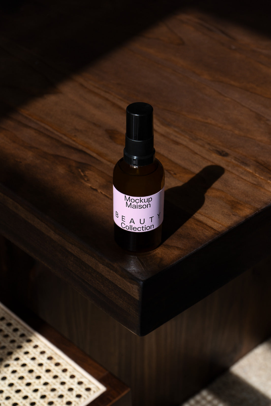 PSD mockup of a beauty product spray bottle labeled "Mockup Maison Beauty Collection" placed on a wooden surface with dramatic lighting.