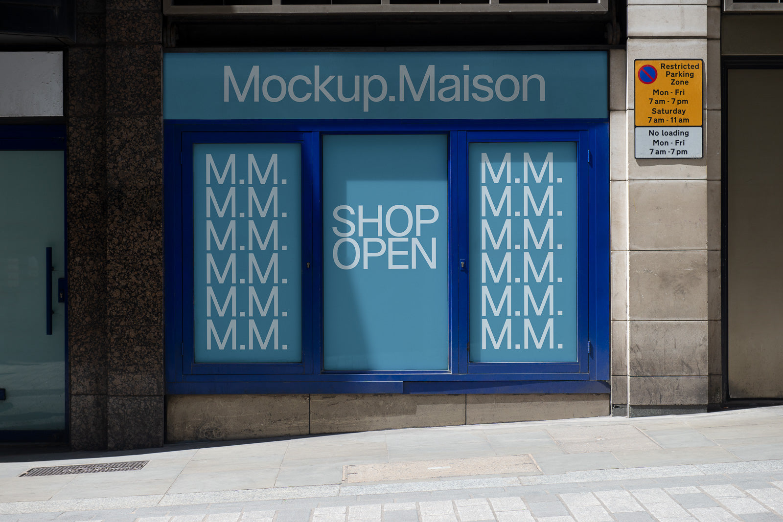 PSD mockup of a storefront with "Shop Open" and "M.M." text on windows, framed by a blue border under a sign reading "Mockup.Maison."