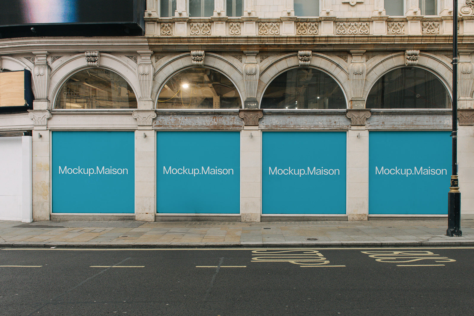PSD mockup of three storefront windows with blue banners displaying "Mockup.Maison" against an elegant stone facade in a city setting.