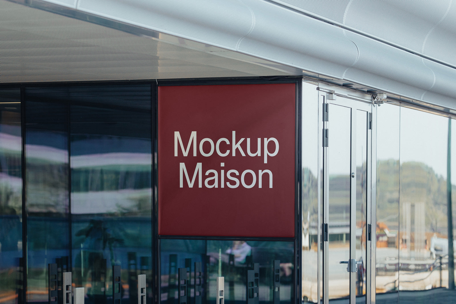 PSD mockup of a red sign on a glass building facade, displaying the words "Mockup Maison" in white text, with a modern architectural design.