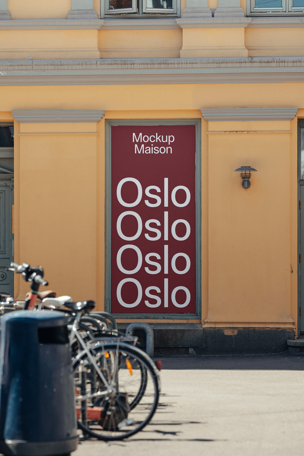 PSD mockup of a street scene with bicycles parked in front of a building. The door displays repeated text "Oslo" with "Mockup Maison" at the top.