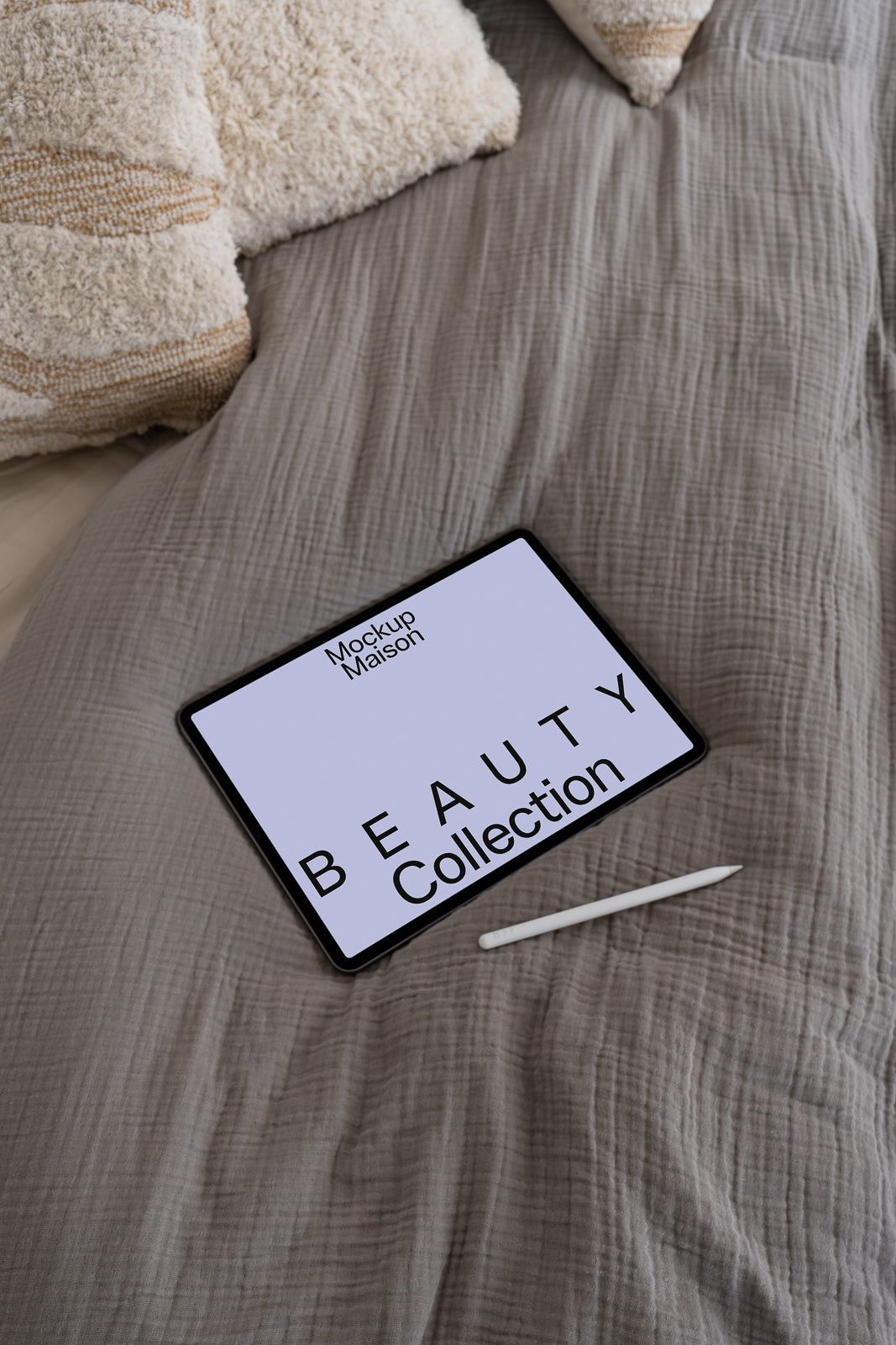 PSD mockup of a tablet on a bed with a stylus, displaying text "Mockup Maison" and "Beauty Collection" in bold letters.