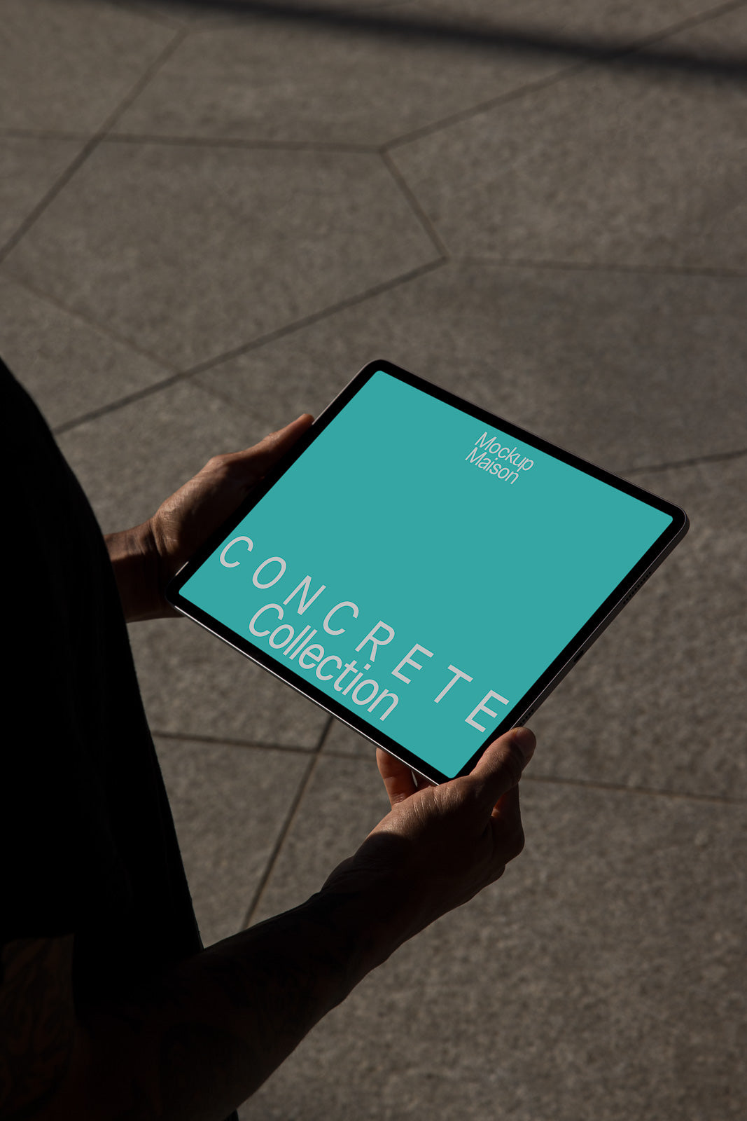 PSD mockup of hands holding a tablet displaying text "Concrete Collection" on a turquoise background, with a geometric stone floor in the background.