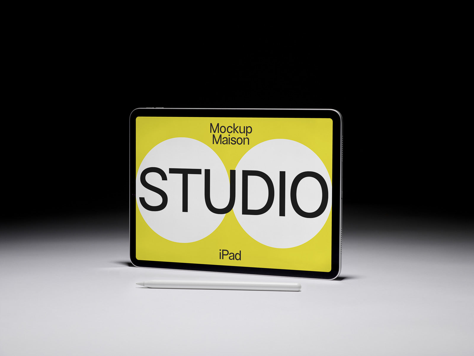 PSD mockup of a digital tablet with a stylus on a gray surface, displaying bold text "STUDIO" on a yellow background.