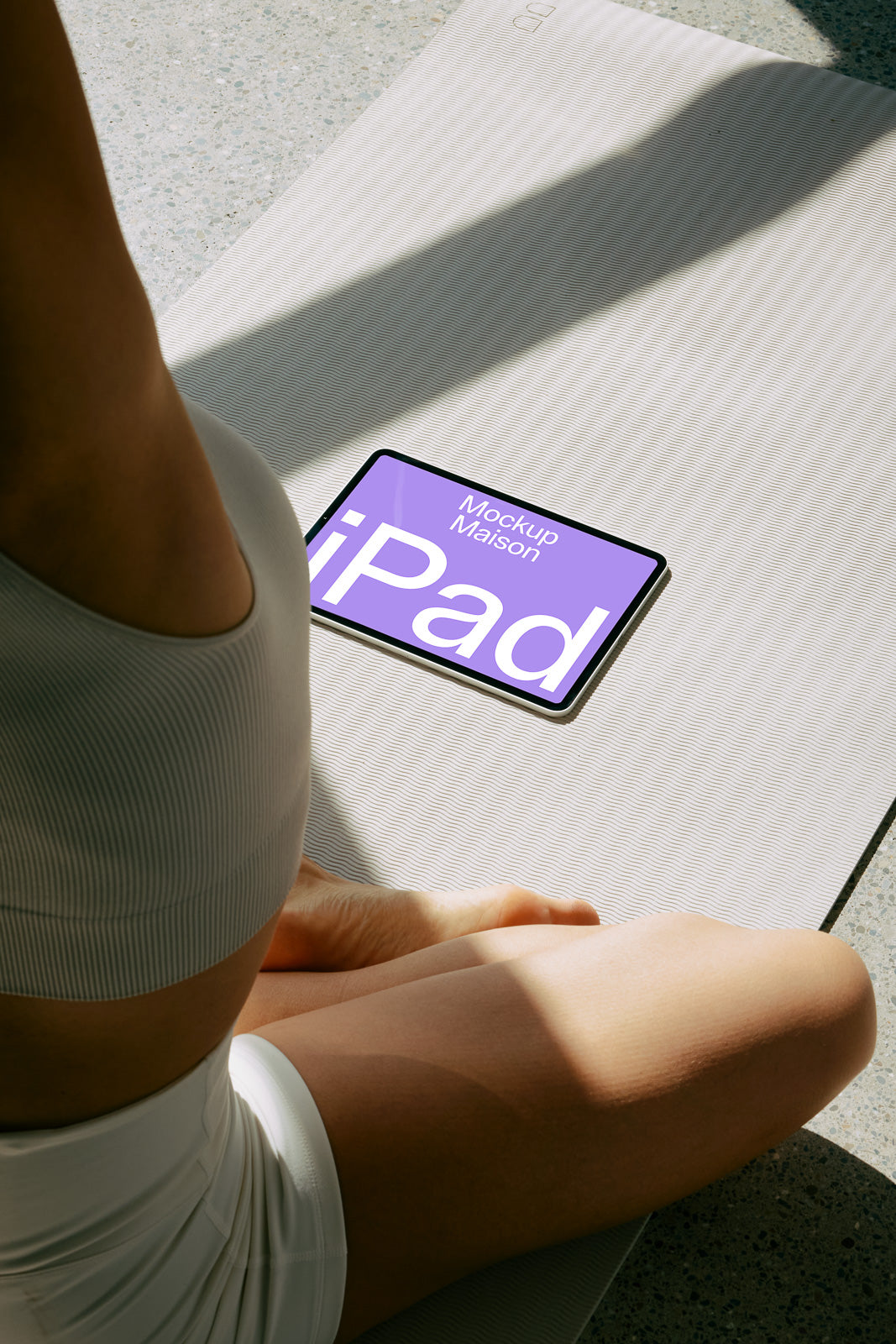 PSD mockup of an iPad on a yoga mat next to a person sitting cross-legged, showing a purple screen with text "Mockup Maison iPad."