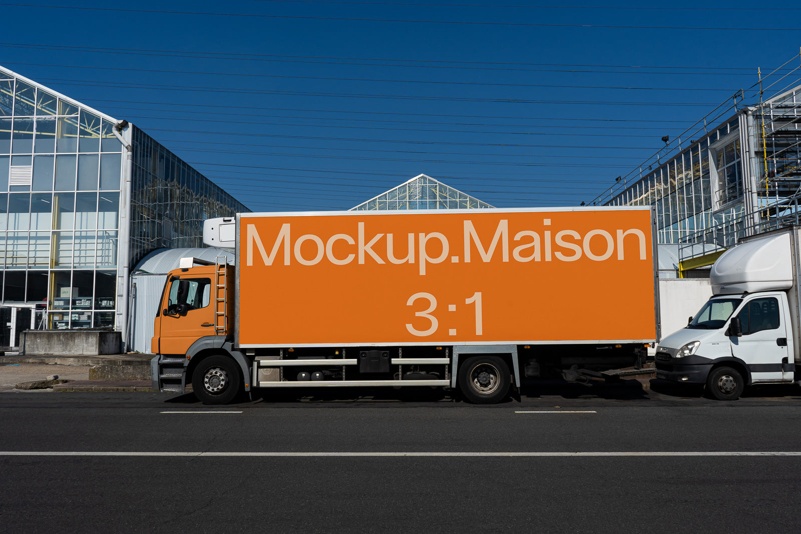 PSD mockup of a parked orange delivery truck with "Mockup.Maison 3:1" text against a background of modern industrial buildings.