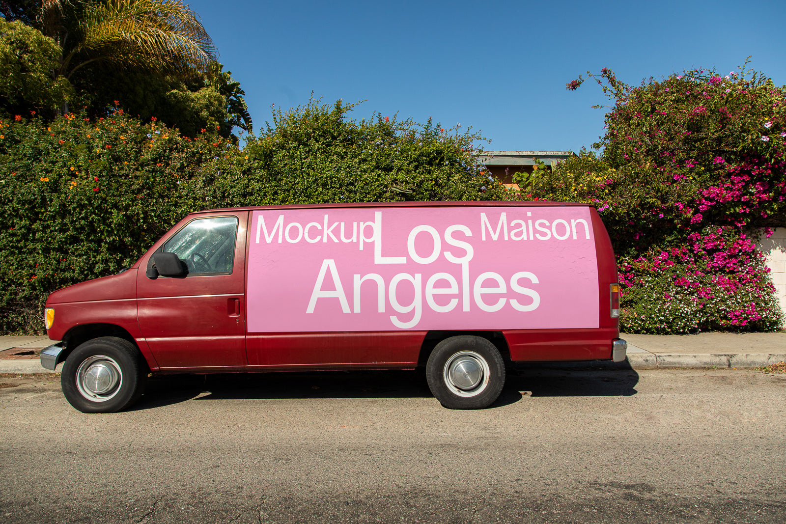 PSD mockup of a red van with a pink and white "Los Angeles" design on the side, parked on a street with vibrant greenery and flowers.