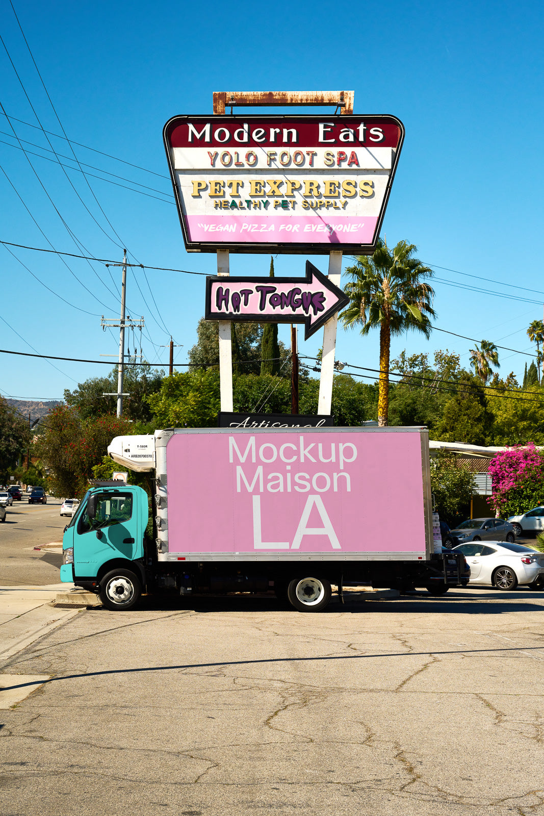PSD mockup of a truck parked on a sunny street, showcasing pink panel with text "Mockup Maison LA" in front of a colorful street sign.