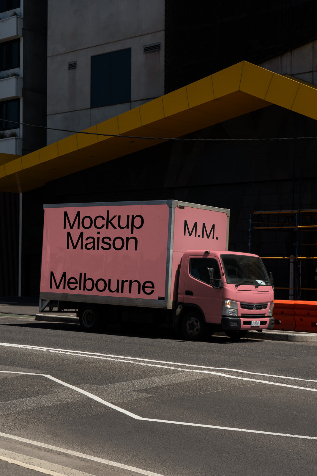 PSD mockup of a pink delivery truck parked on a city street with the words "Mockup Maison Melbourne" printed on the side panel.