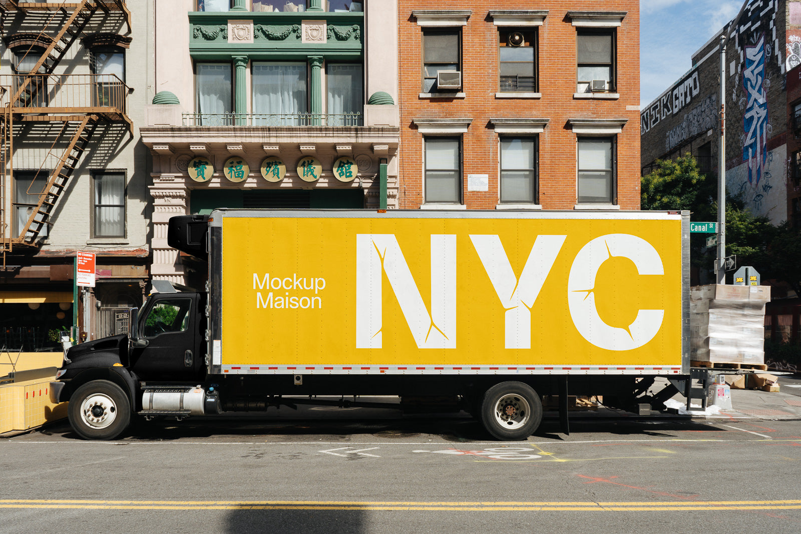 PSD mockup of a parked truck in an urban setting with a yellow side panel featuring the text "Mockup Maison NYC" against a backdrop of city buildings.