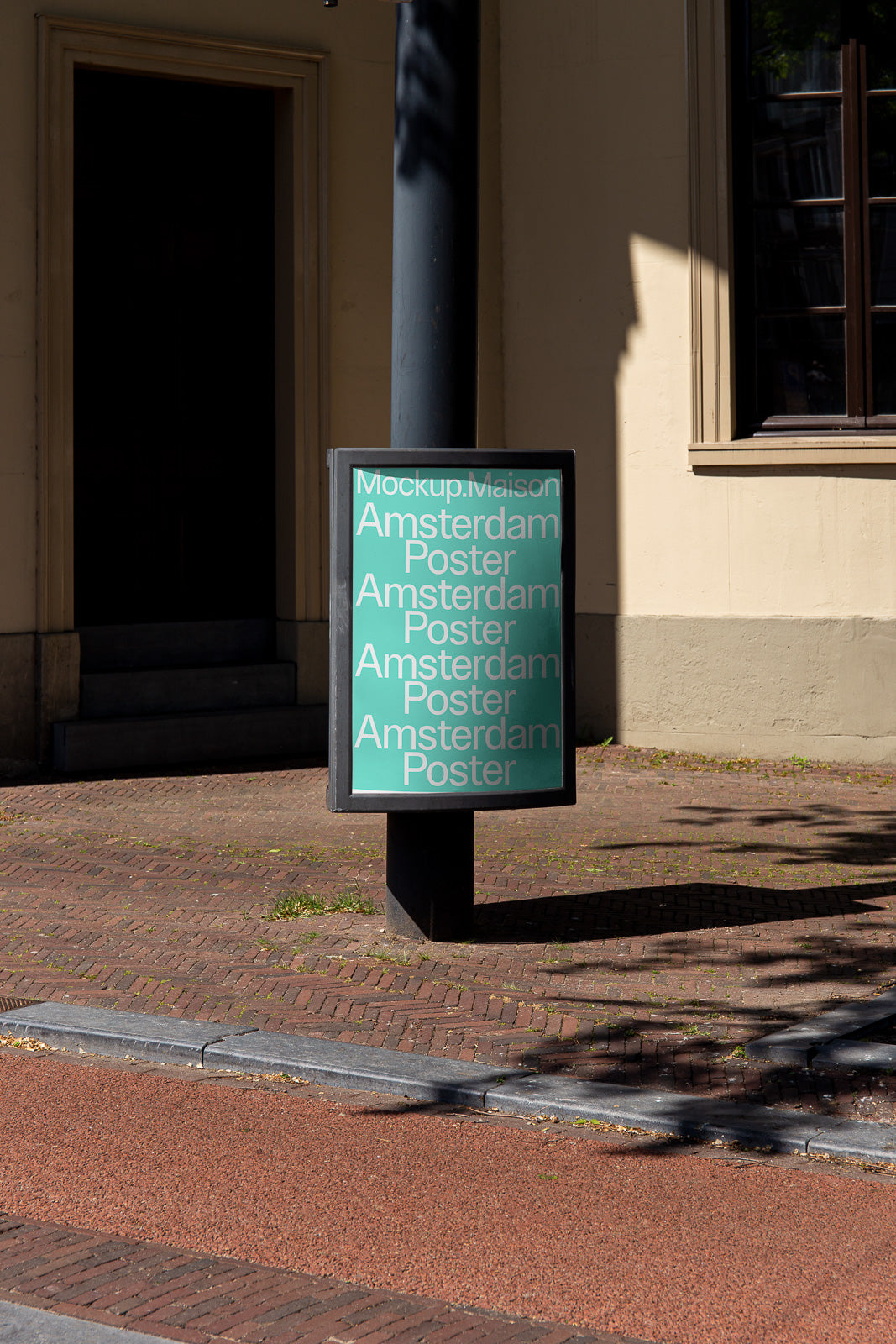 PSD mockup of an urban poster on a black cylindrical pole, displaying text in green and white, located on a brick sidewalk near a building.