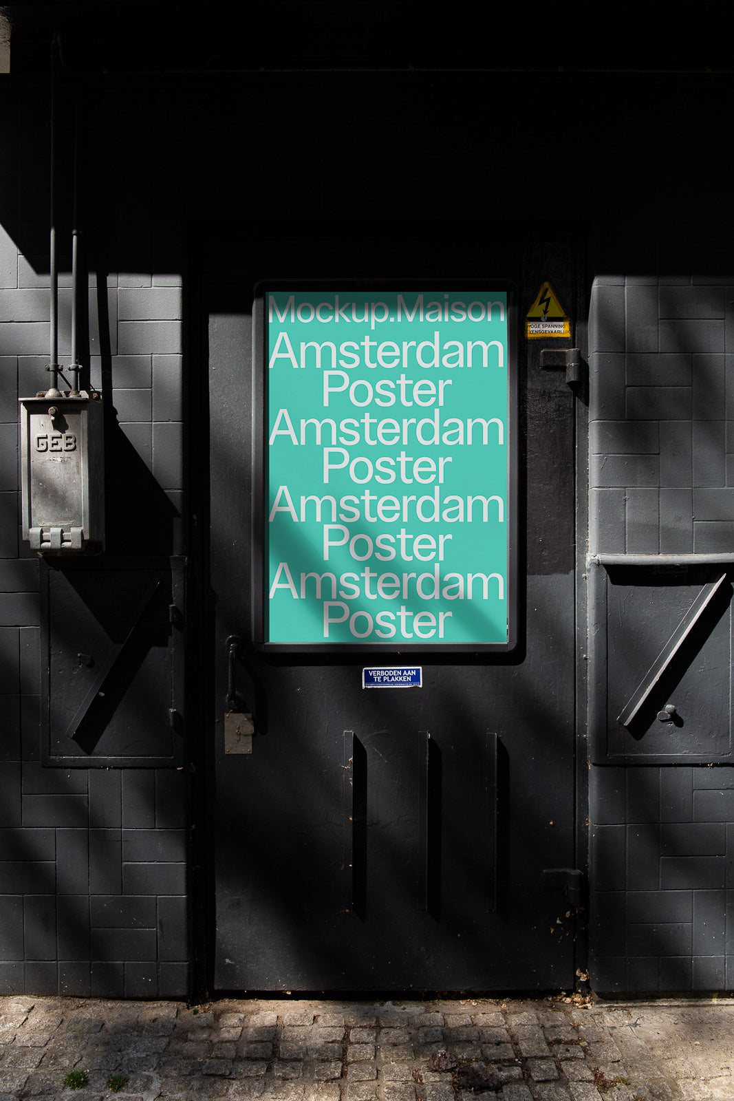 PSD mockup of an urban poster on a dark building door, displaying the words "Mockup.Maison Amsterdam Poster" in white text on a turquoise background.