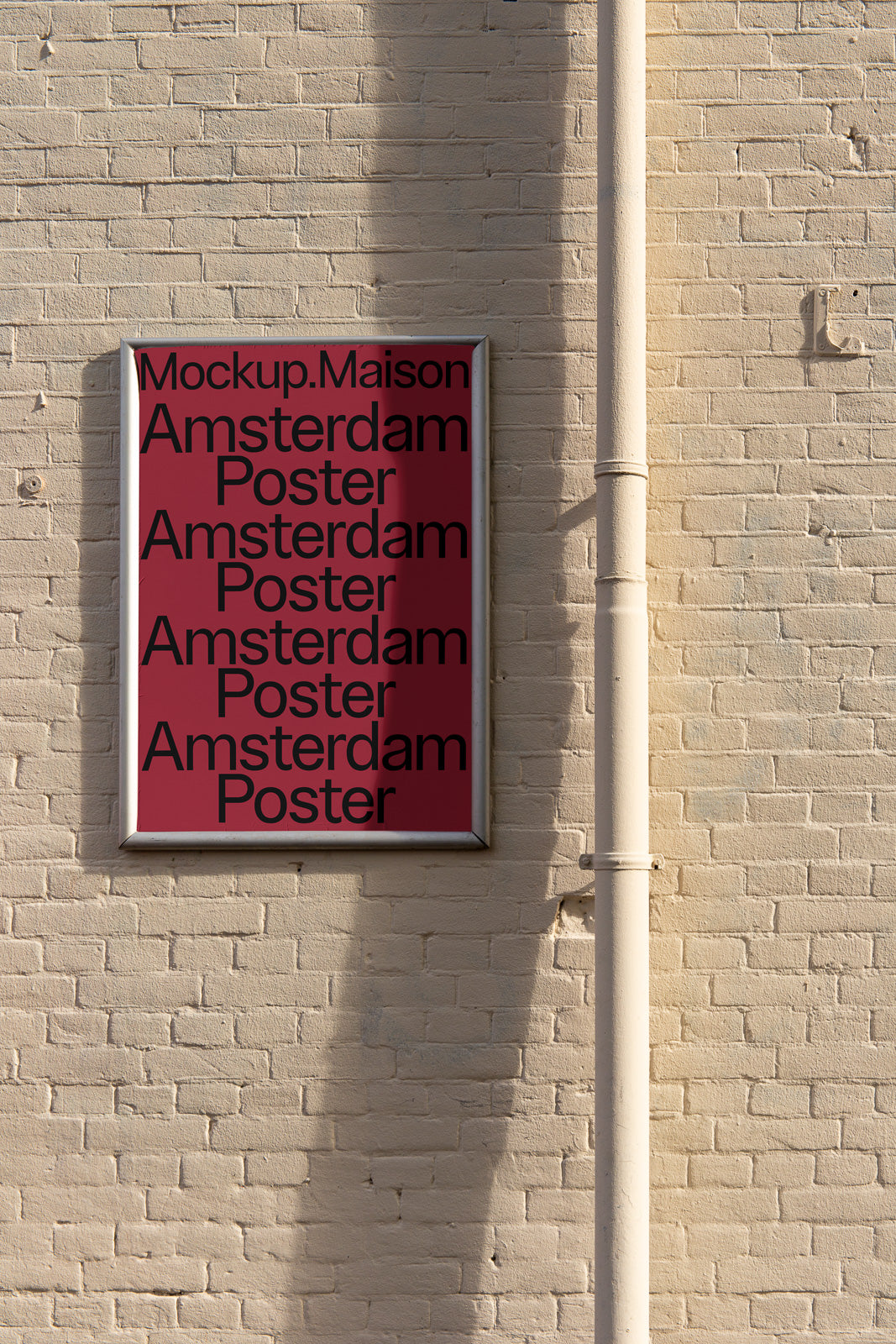 PSD mockup of a framed poster on a brick wall with a maroon background and the text "Amsterdam Poster" repeated.