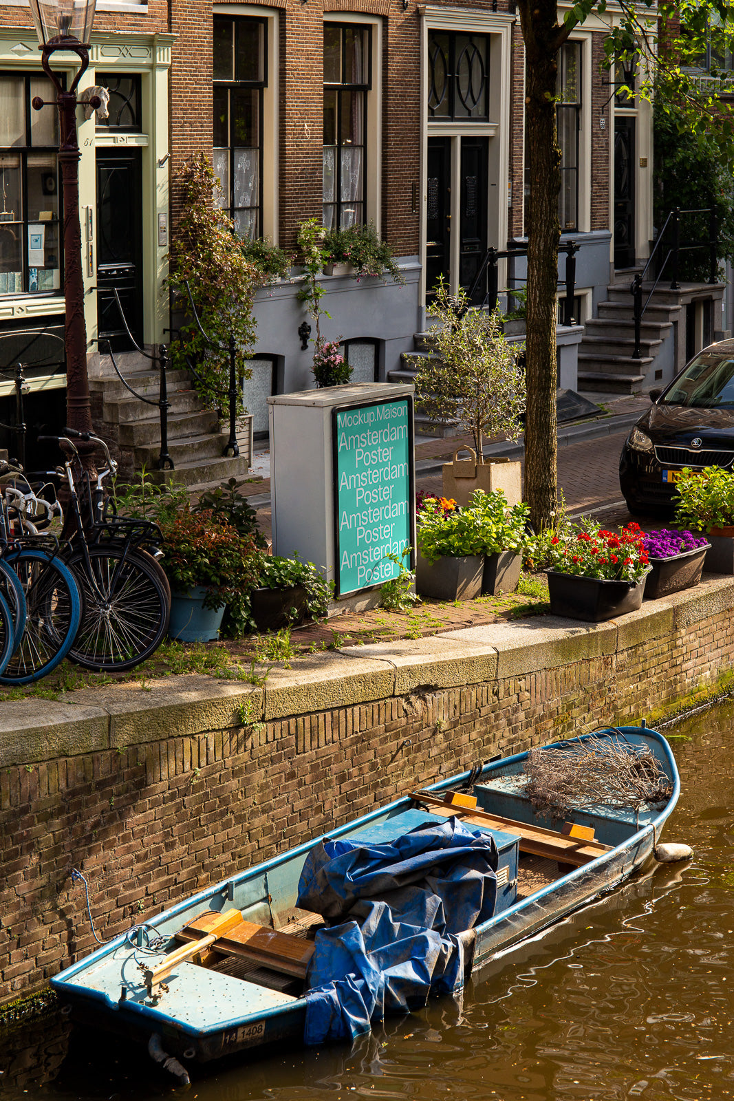 PSD mockup of an Amsterdam street scene with a poster stand beside a canal, surrounded by bicycles and brick buildings, casting reflections on the water.