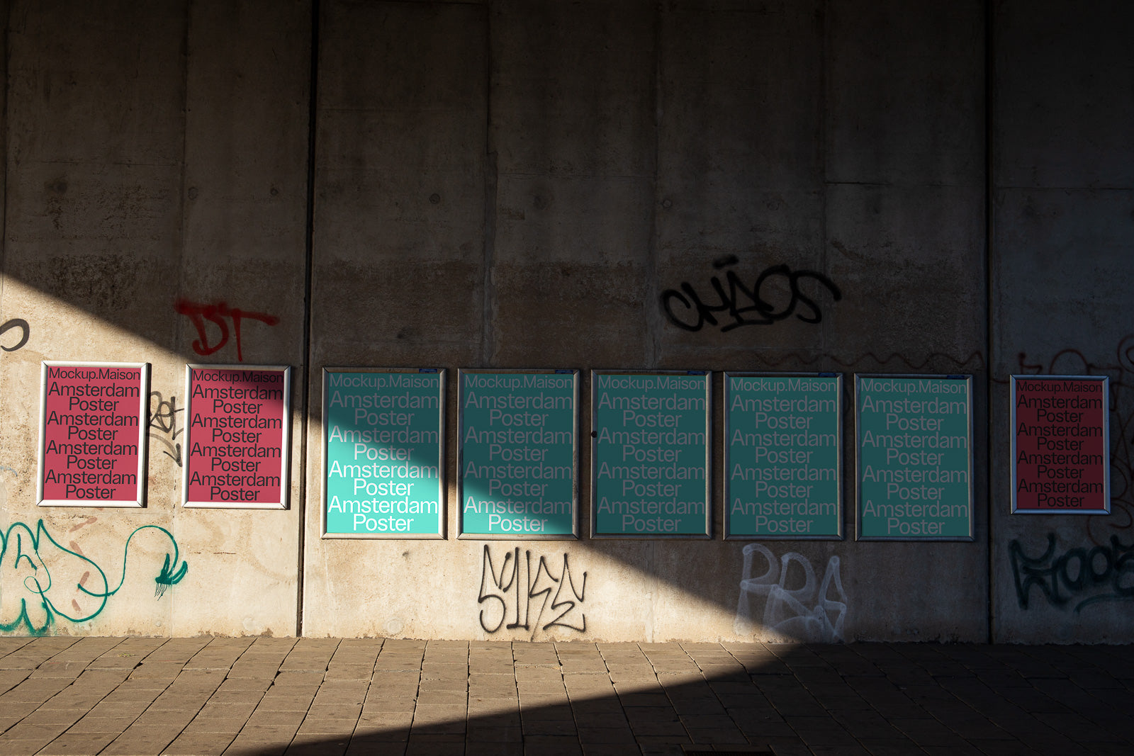 PSD mockup of posters displayed on a graffiti-covered concrete wall, featuring "Amsterdam Poster" text in red and blue under varying sunlight.