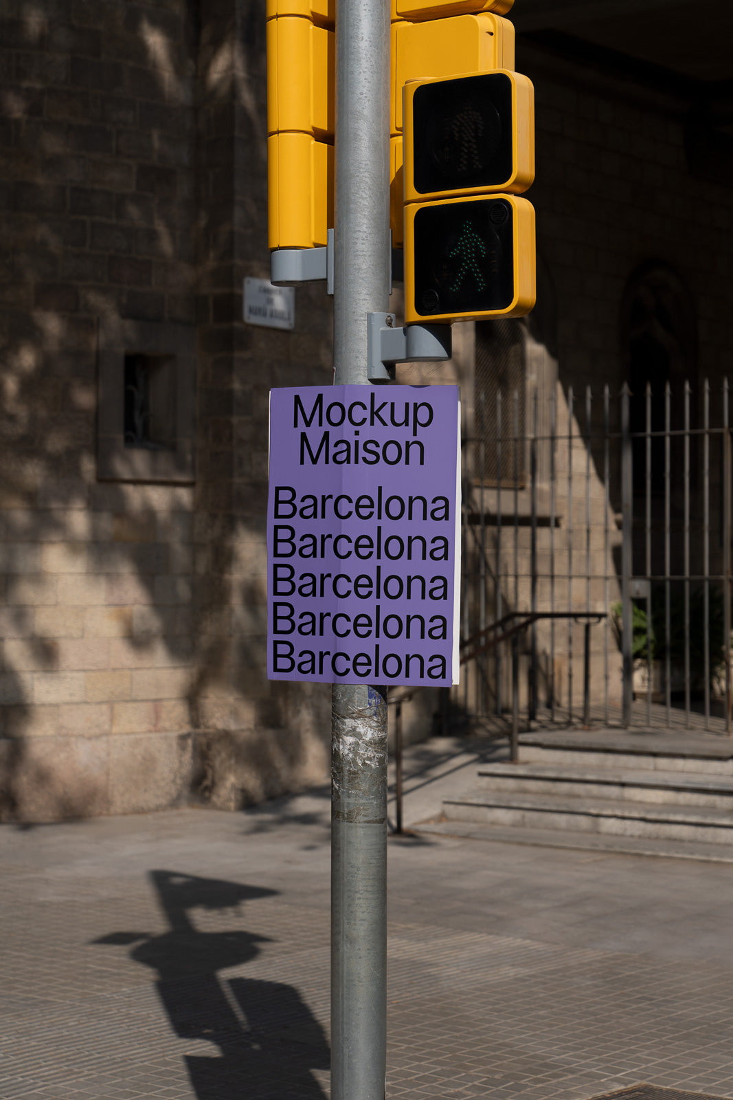 PSD mockup of a street pole with a purple poster reading "Mockup Maison Barcelona" multiple times, set in an urban environment with shadows and a nearby traffic light.