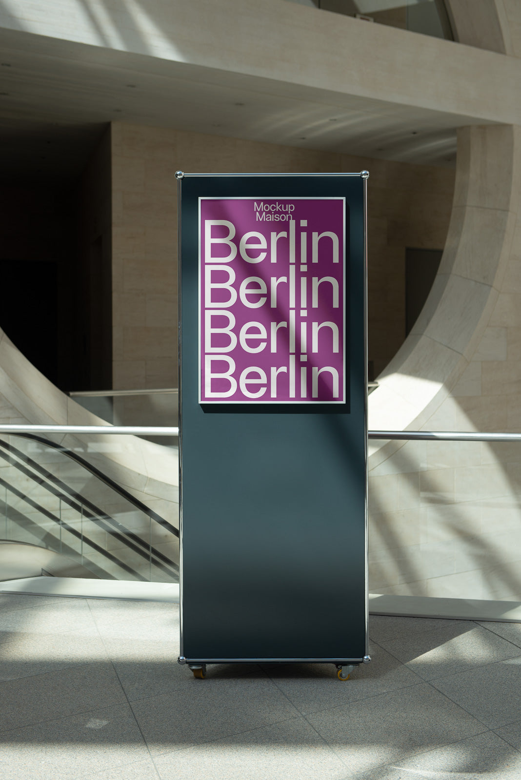PSD mockup of a vertical poster stand in a modern building with a purple "Berlin" repeated design, sunlight casting shadows on the floor.