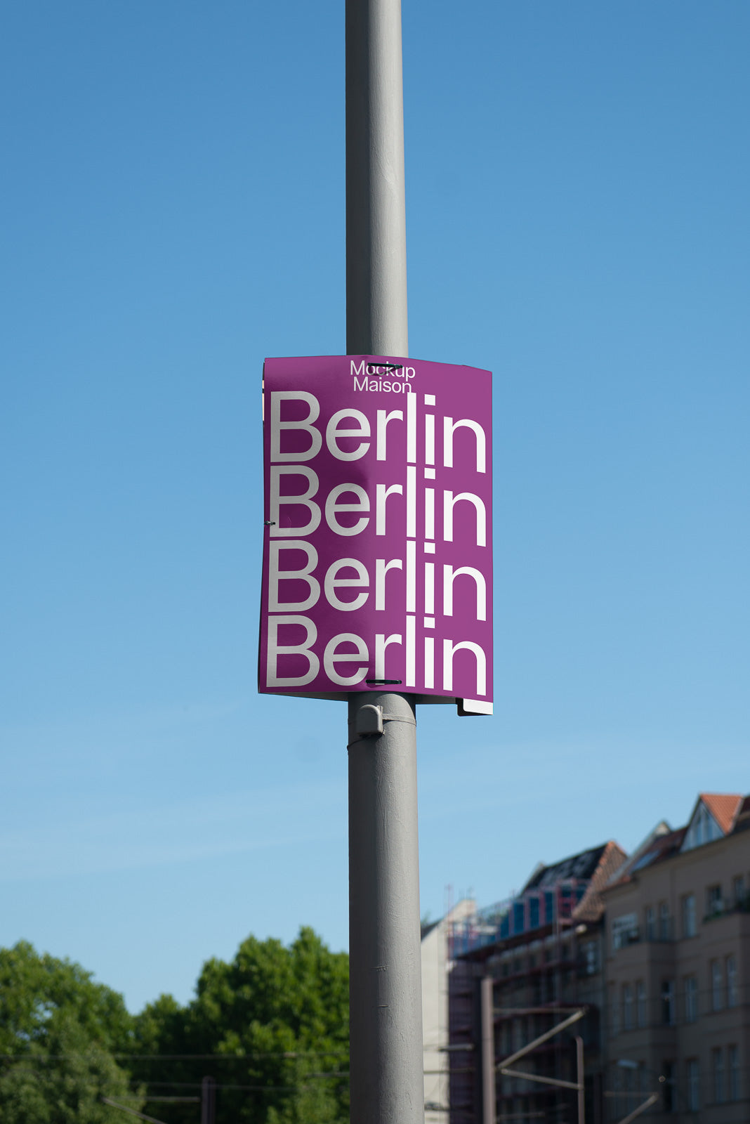 PSD mockup of a street pole with a purple poster displaying the word "Berlin" repeatedly against a backdrop of clear blue sky and urban buildings.