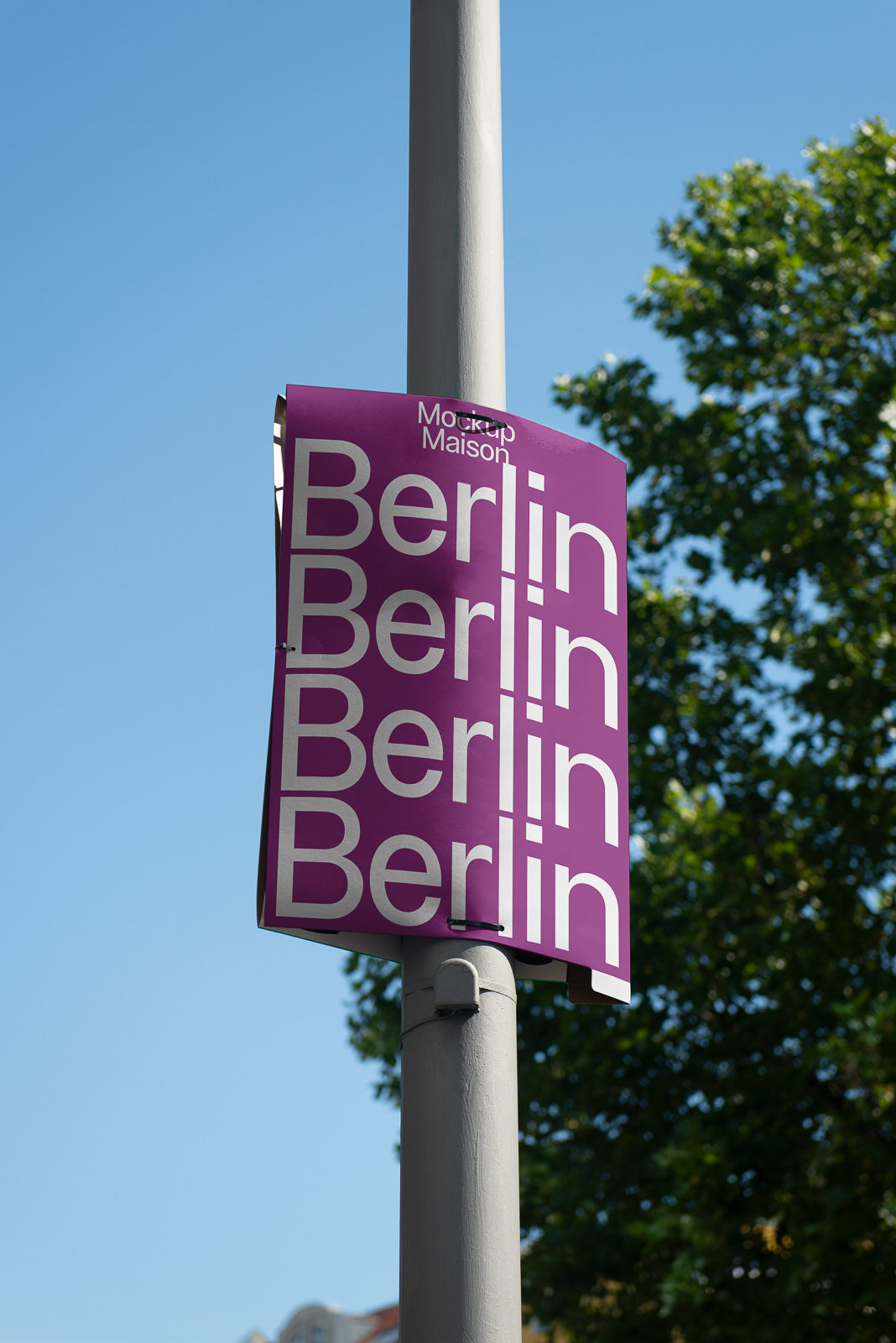 PSD mockup of a vertical street pole poster displaying the word "Berlin" repeatedly in white text on a purple background against a clear blue sky.