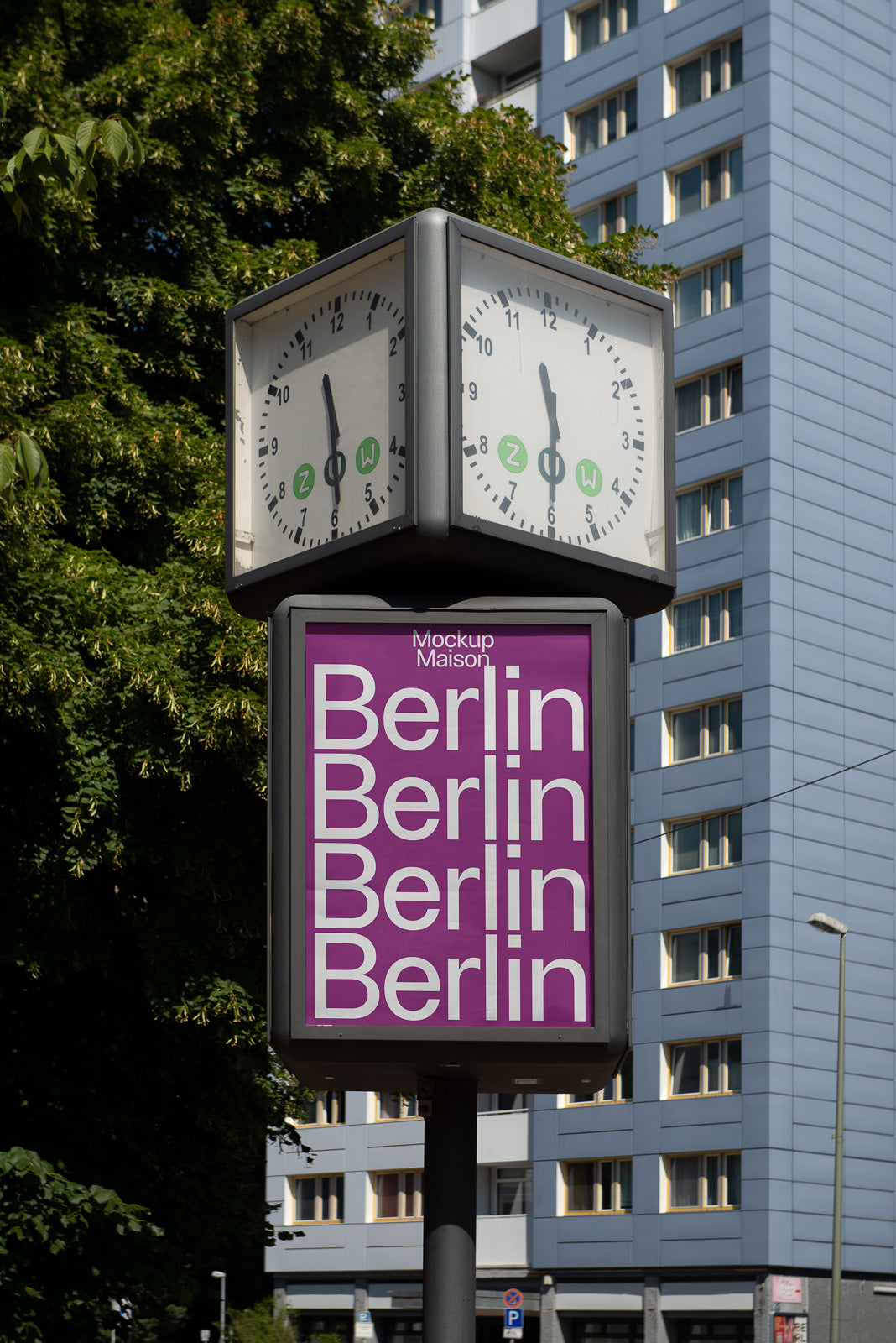 PSD mockup of a public clock and signage tower featuring the repeated word "Berlin" in white on a purple background, with a modern building and trees in the background.