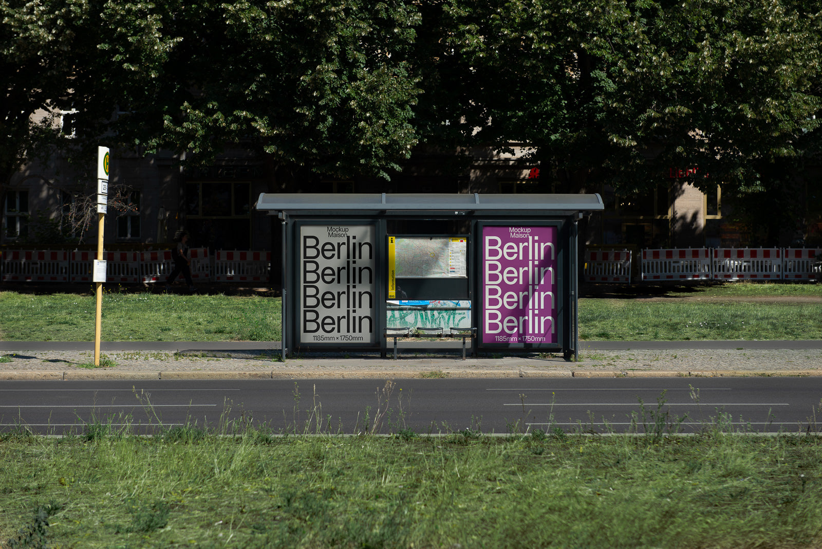 PSD mockup of a bus stop shelter with two large posters displaying the word "Berlin" in bold black and white on the left, and magenta on the right, amid a green urban landscape.