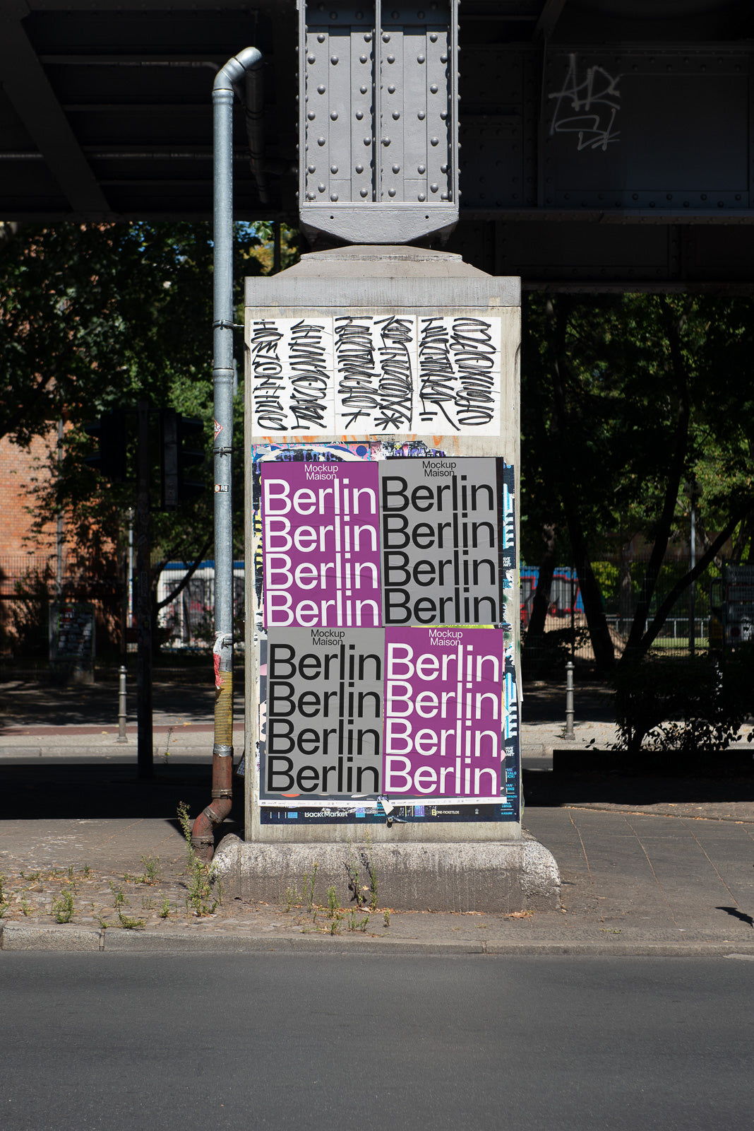 PSD mockup of two different Berlin poster designs on a concrete pillar under a bridge, featuring graffiti tags above and urban surroundings.
