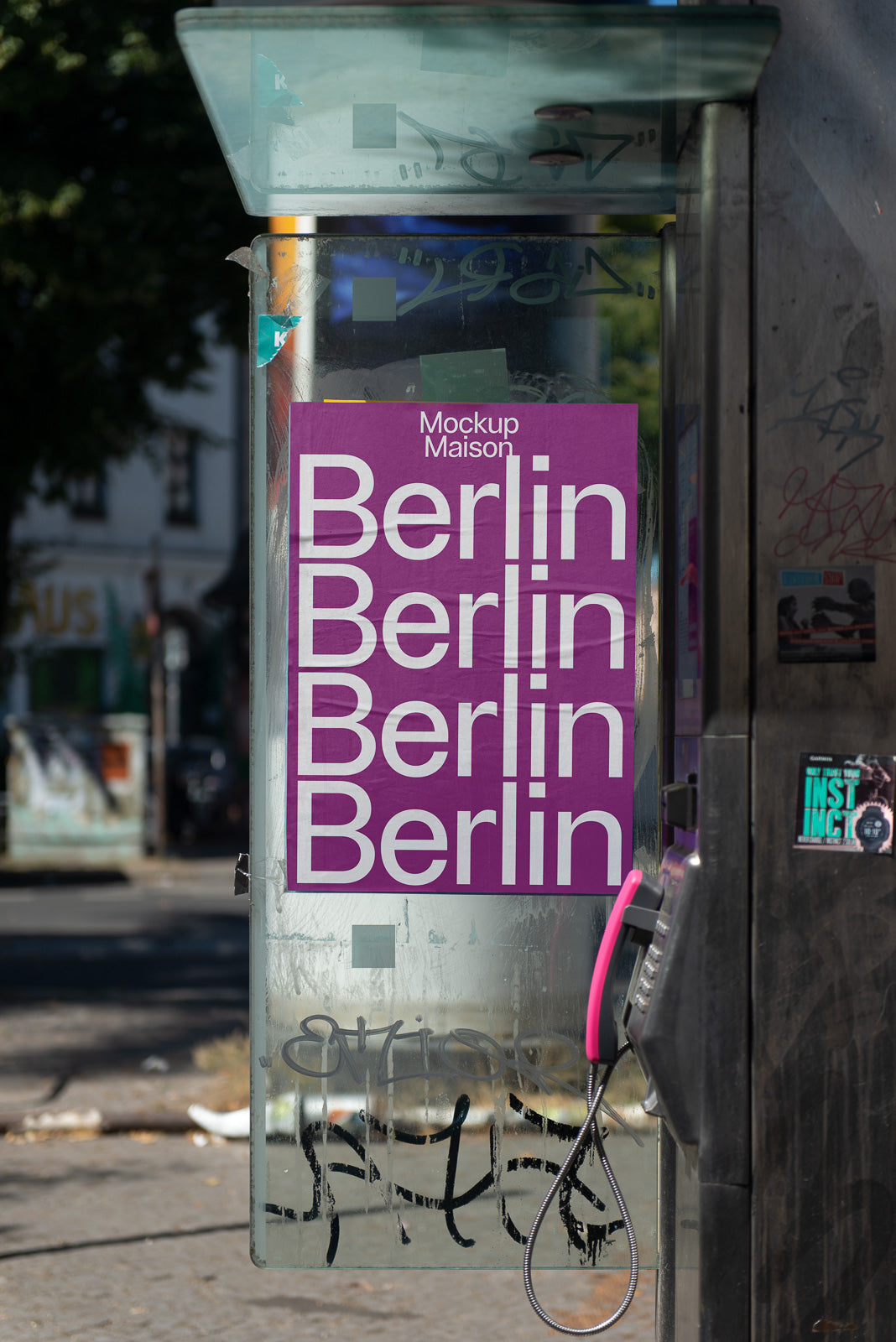 PSD mockup of a phone booth with a purple poster displaying the word “Berlin” repeatedly, situated on a city street with various backgrounds.