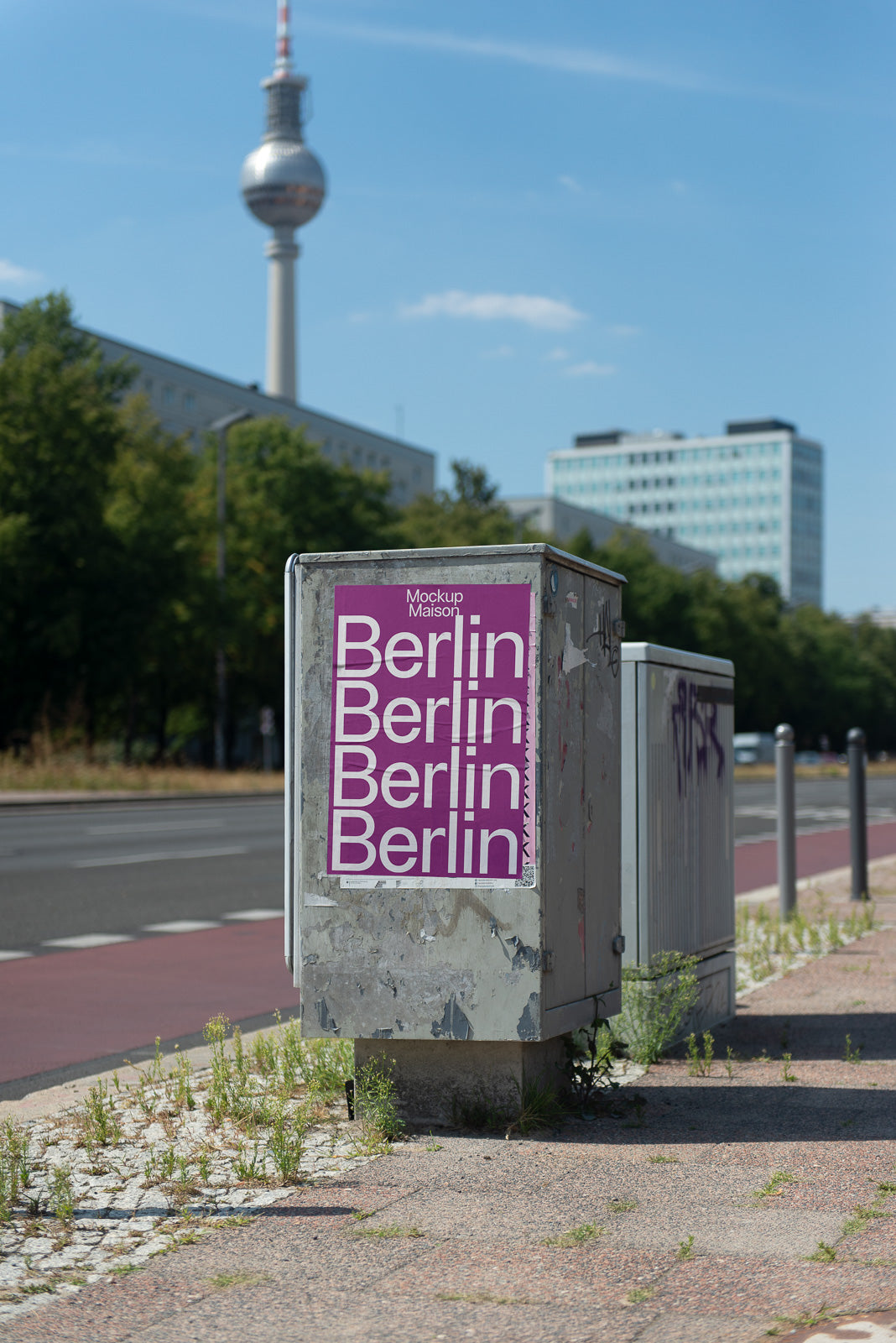 PSD mockup of a street utility box with a purple poster displaying the word "Berlin" repeatedly, set against a background featuring a tall tower and urban buildings.