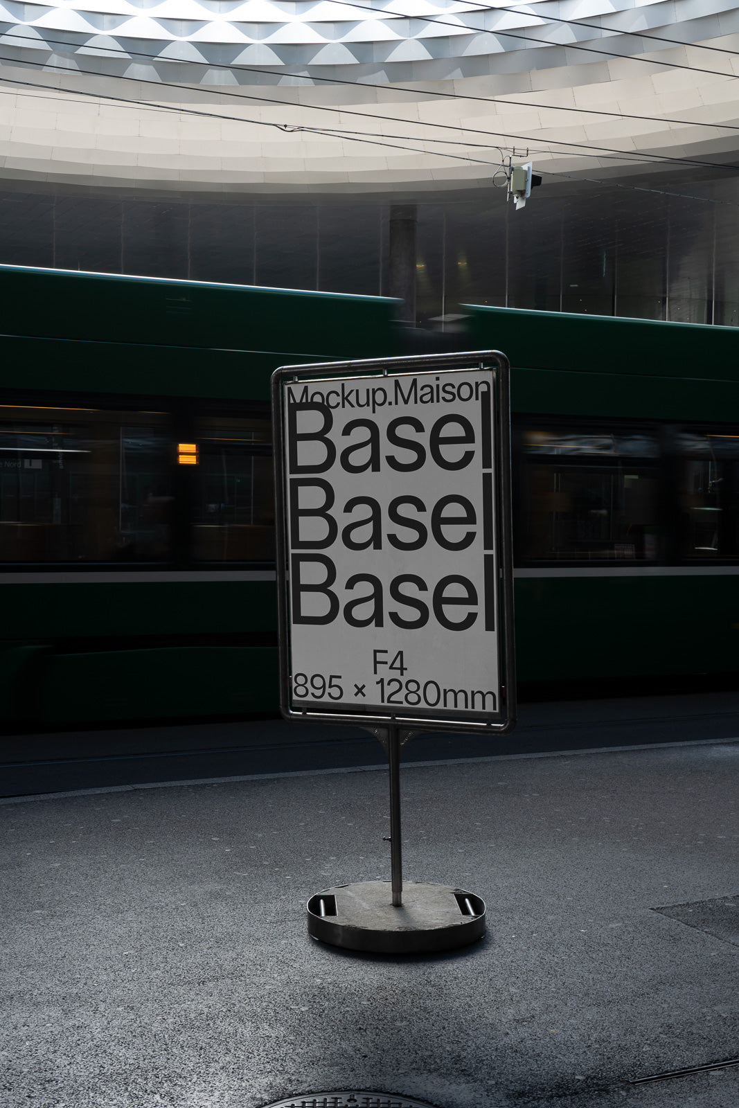 PSD mockup of a city street sign displaying the word "Basel" repeatedly, with dimensions noted as 895 x 1280mm, set against a blurred background with a moving green tram.