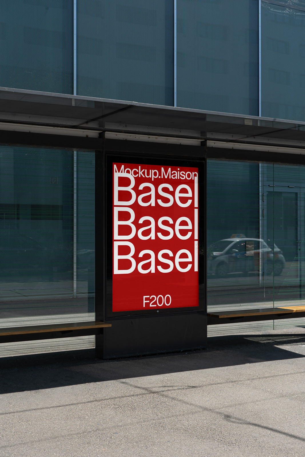 PSD mockup of a bus stop advertising panel displaying a red poster with white text that reads "Mockup.Maison Basel Basel Basel F200," set against a city backdrop.