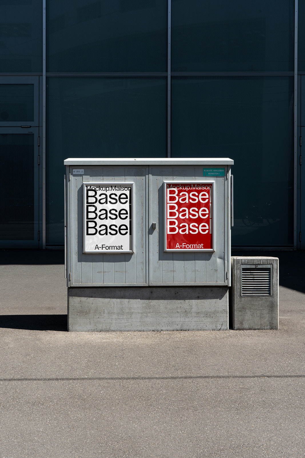 PSD mockup of two posters displayed on a gray electrical box, one with a white background and black text, the other red with white text.