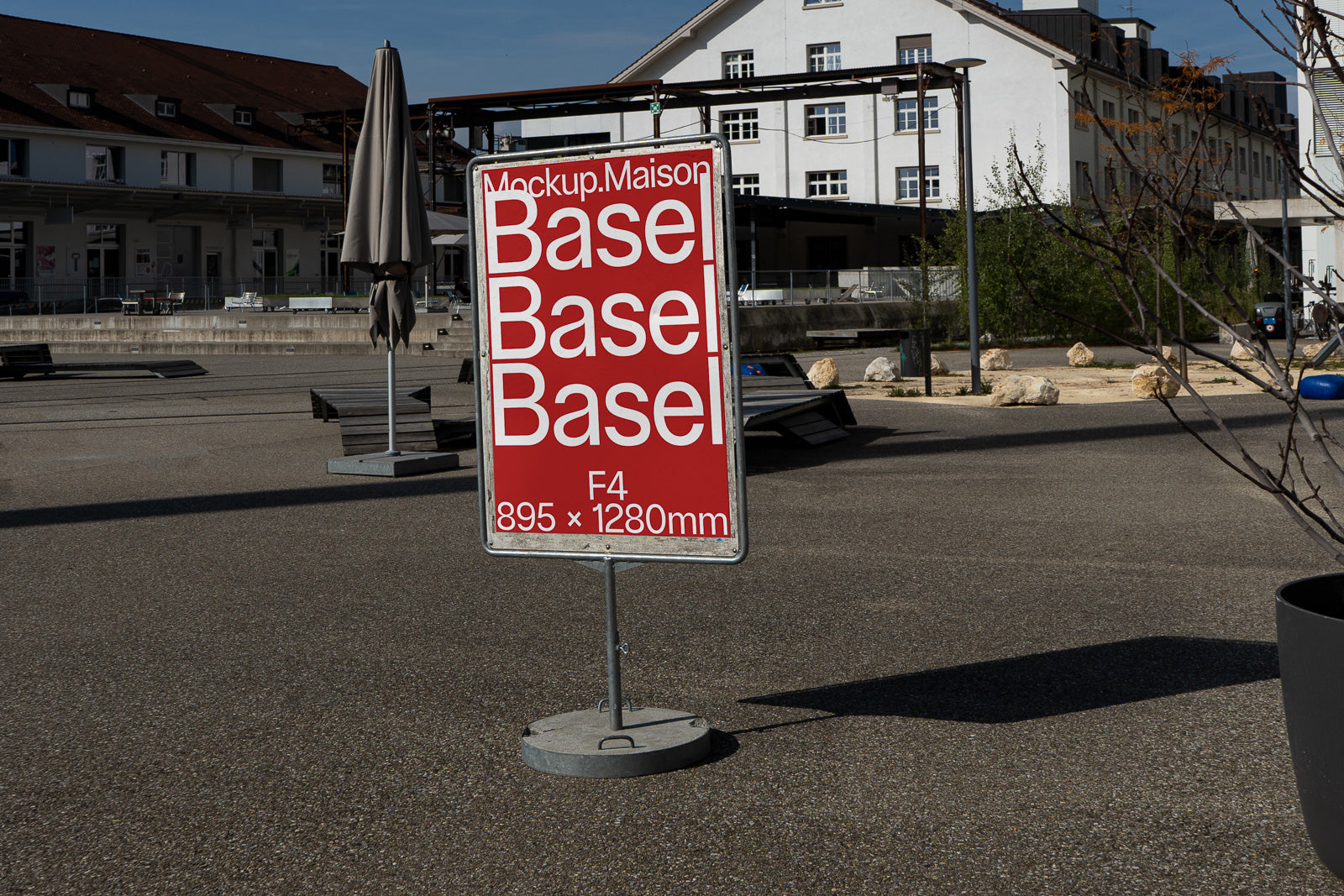 PSD mockup of an outdoor street sign with red background displaying the text "Basel" multiple times, situated in an urban environment.