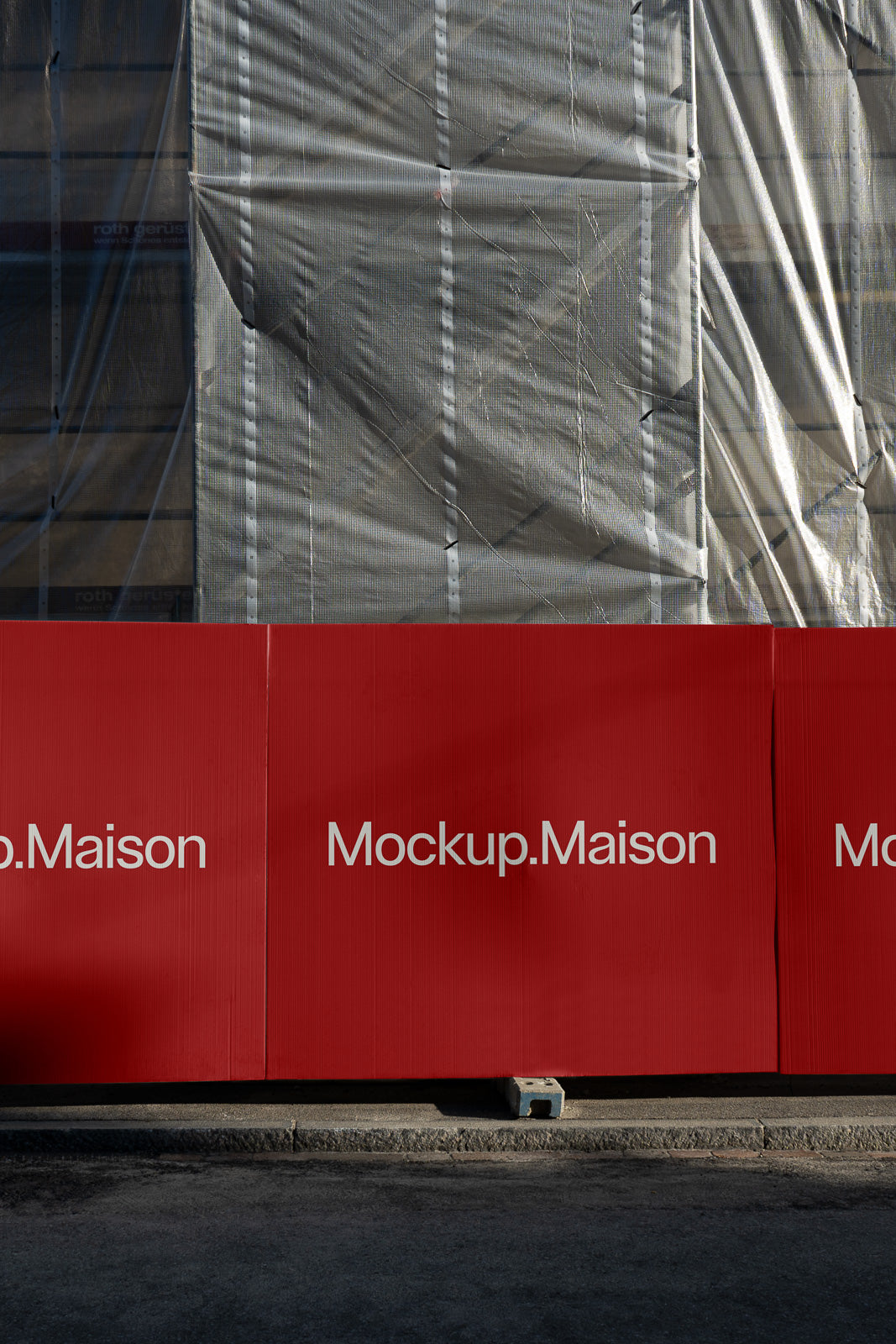 PSD mockup of a red construction barrier with the text "Mockup.Maison" in white letters, set against a partially covered building facade.