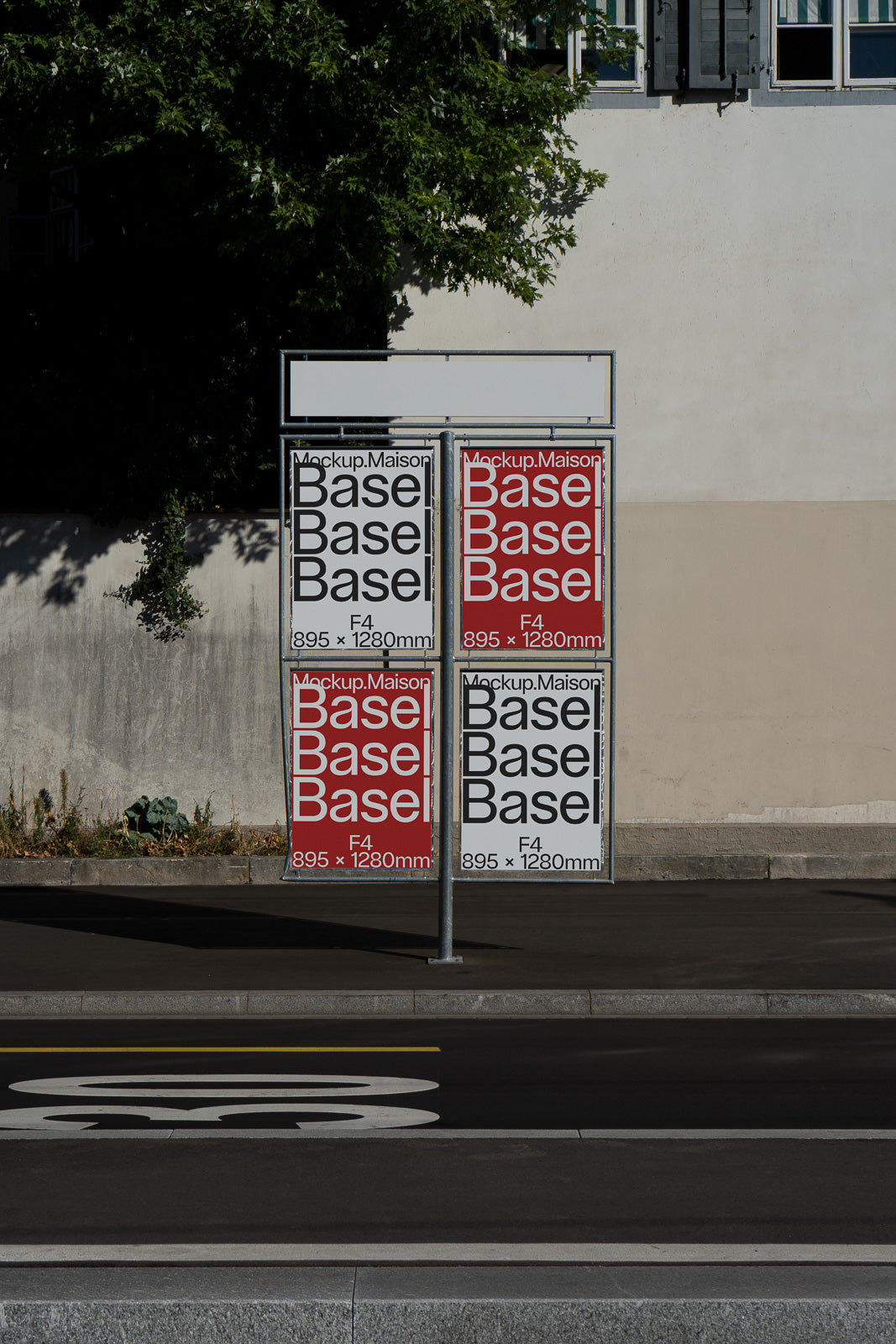 PSD mockup of a street sign with four poster frames, each featuring text "Mockup Maison Base Basel" in alternating black and red designs, on a sidewalk.