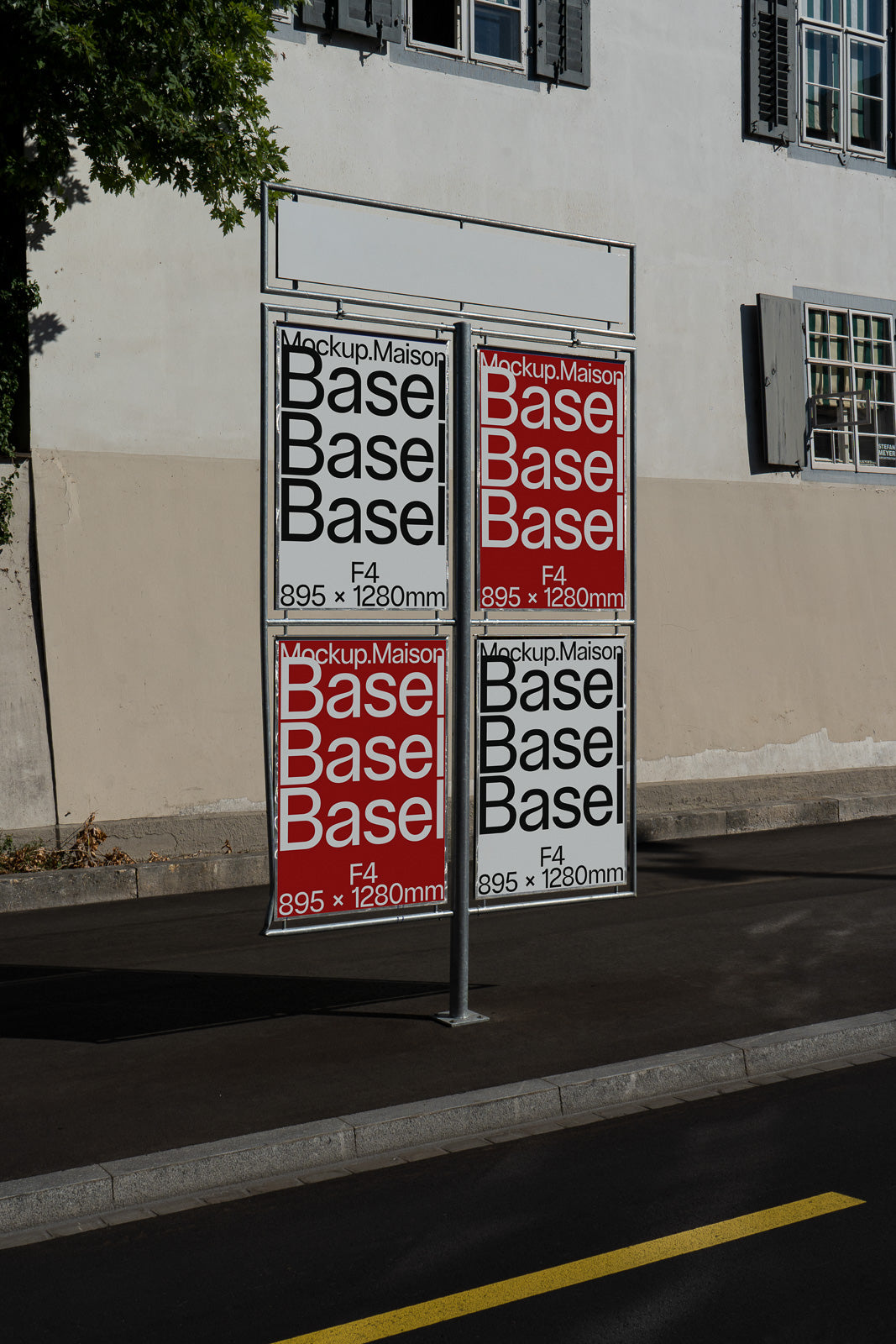 PSD mockup of four outdoor advertising posters on a sidewalk, featuring red and white designs, mounted on a dual-sided stand against a building backdrop.