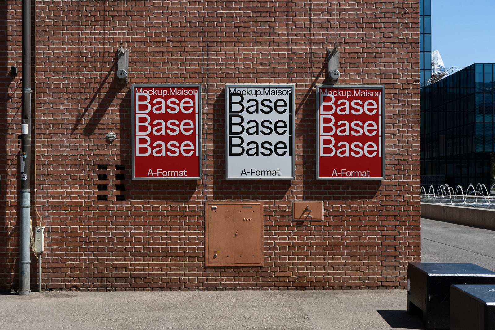 PSD mockup of three posters on a brick wall, with two red and one white, displaying the word "Basel" repeatedly, suggesting an urban setting.