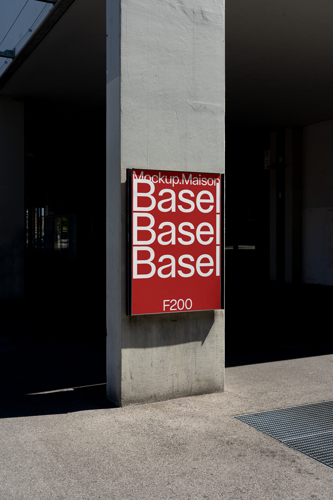 PSD mockup of a red wall-mounted sign with "Basel" in bold white text repeated three times, casting a shadow on the concrete wall.