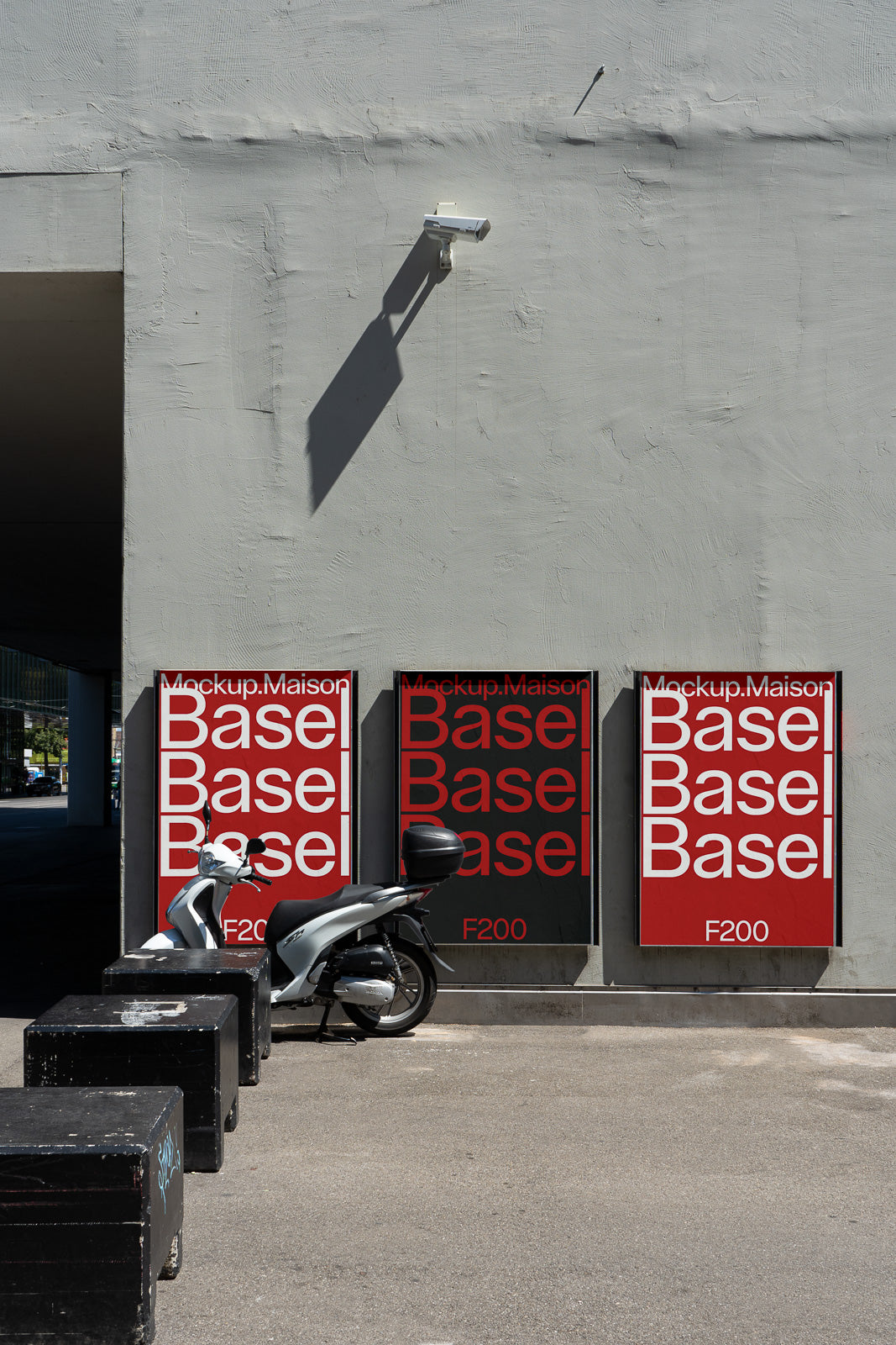 PSD mockup of three red posters on a gray wall with bold text, a parked scooter in front, and a security camera casting a shadow.
