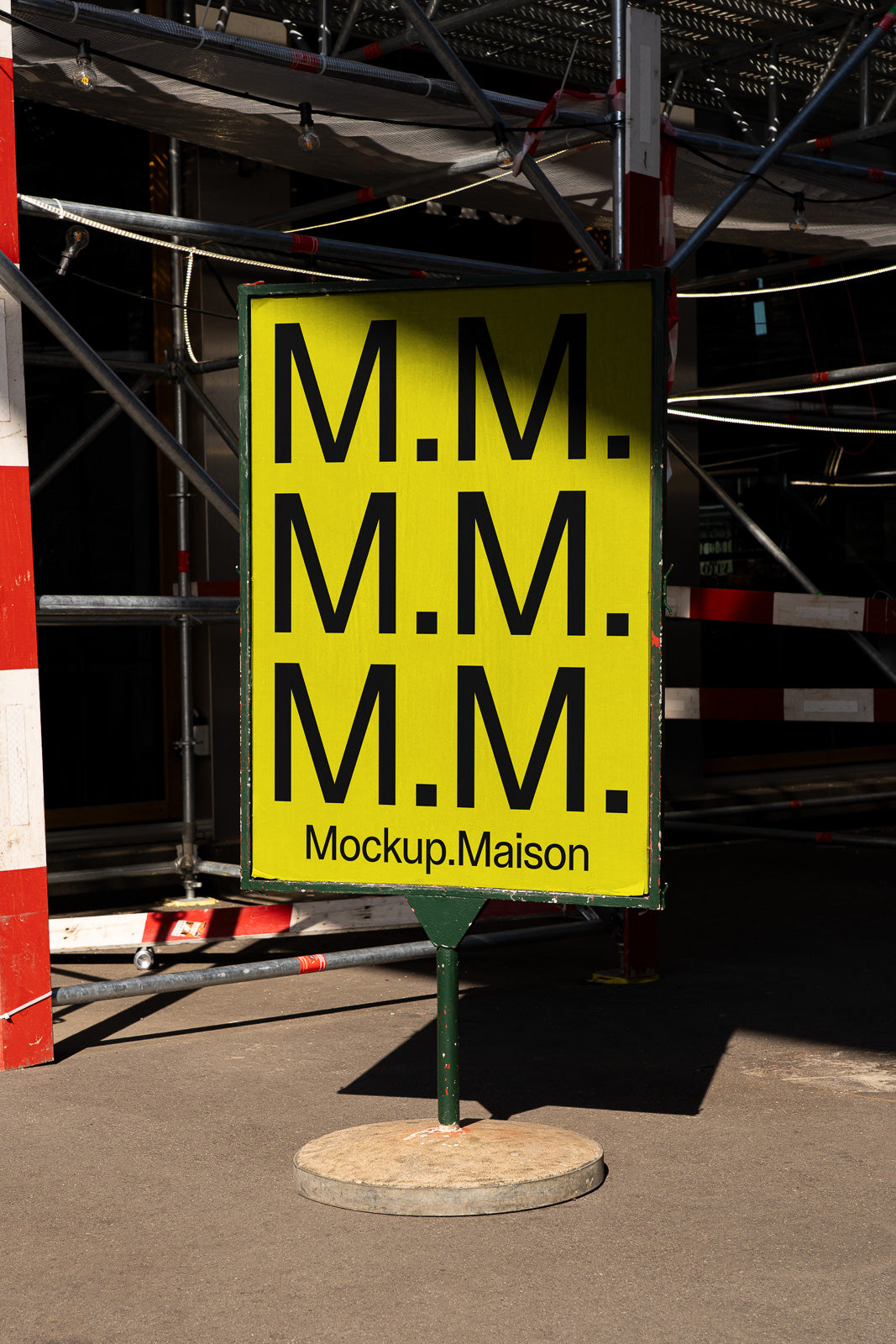 PSD mockup of a yellow street sign with repeated "M.M." text and "Mockup.Maison" at the bottom, set against a backdrop of scaffolding.