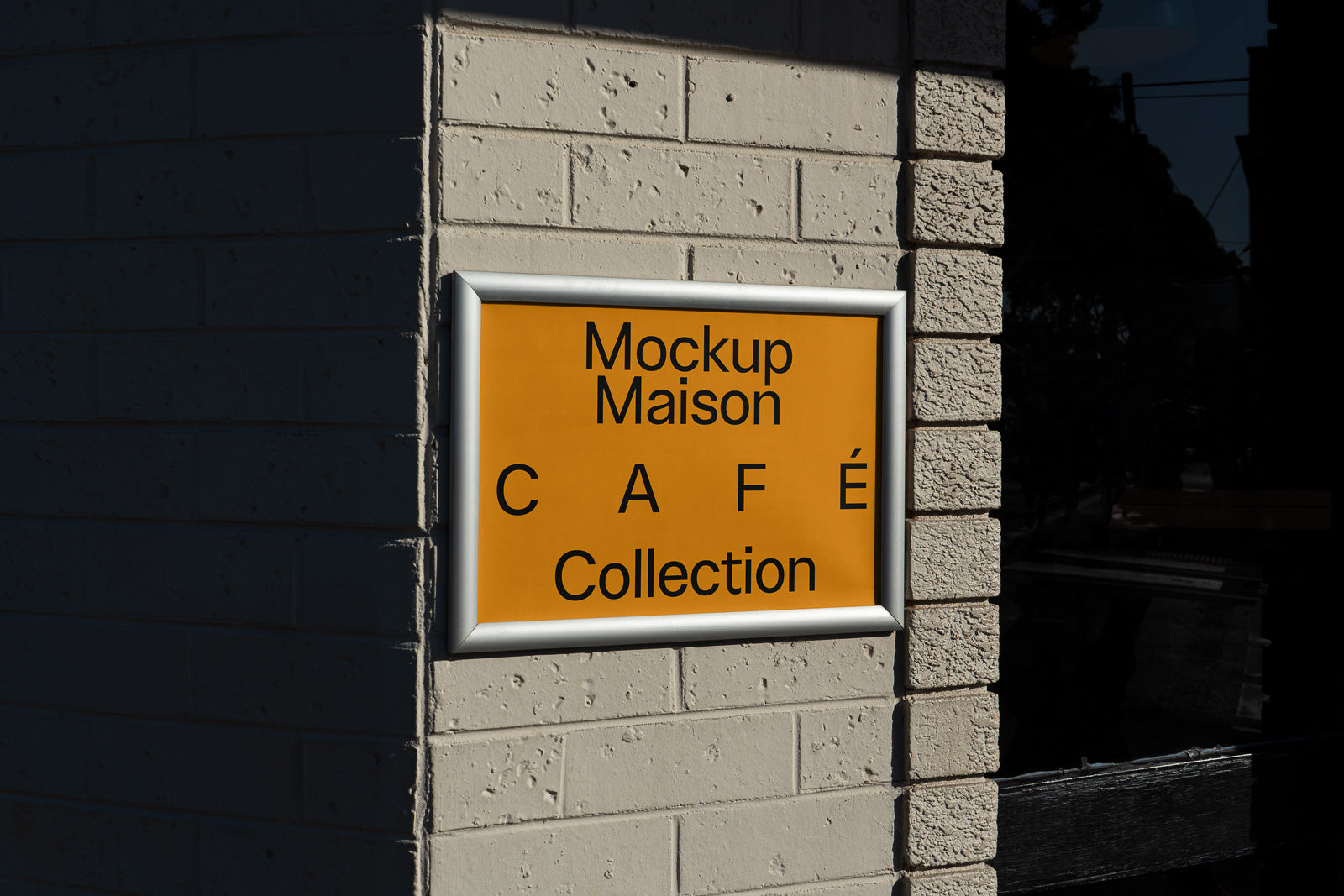 PSD mockup of an orange café sign mounted on a brick wall with text "Mockup Maison Café Collection," shaded in natural daylight.