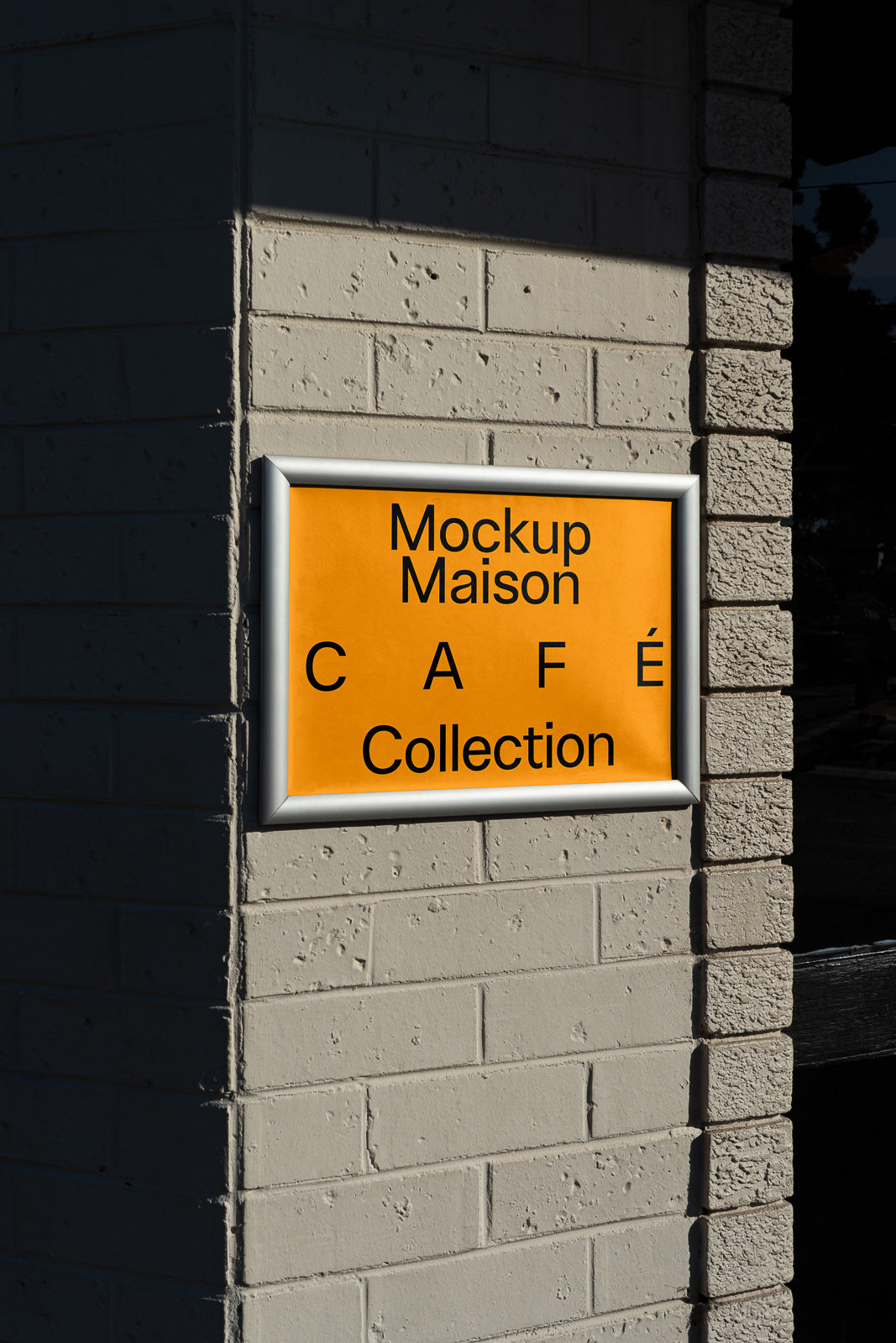 PSD mockup of an orange sign with black text on a brick wall, showcasing "Mockup Maison Café Collection" with a sleek frame.