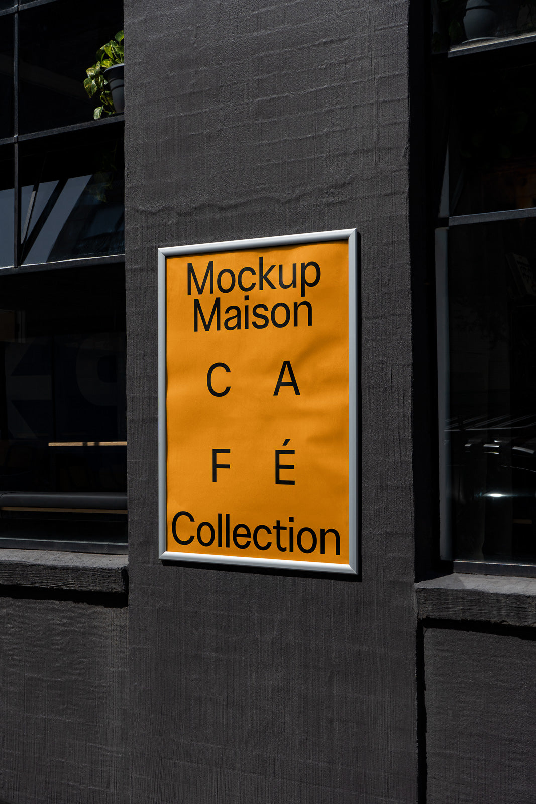 PSD mockup of an orange poster displayed on a dark wall with black text reading "Mockup Maison Café Collection," positioned next to a window.